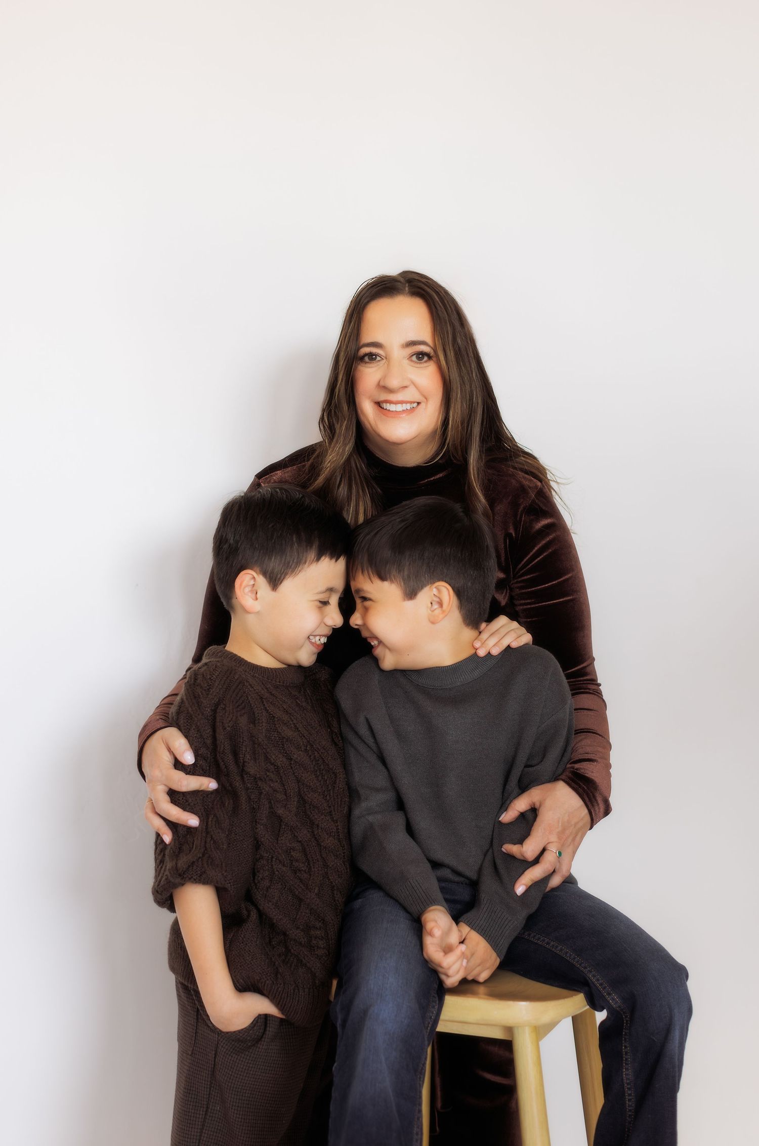 A series of three casual studio portraits showing tender family moments against a light background.