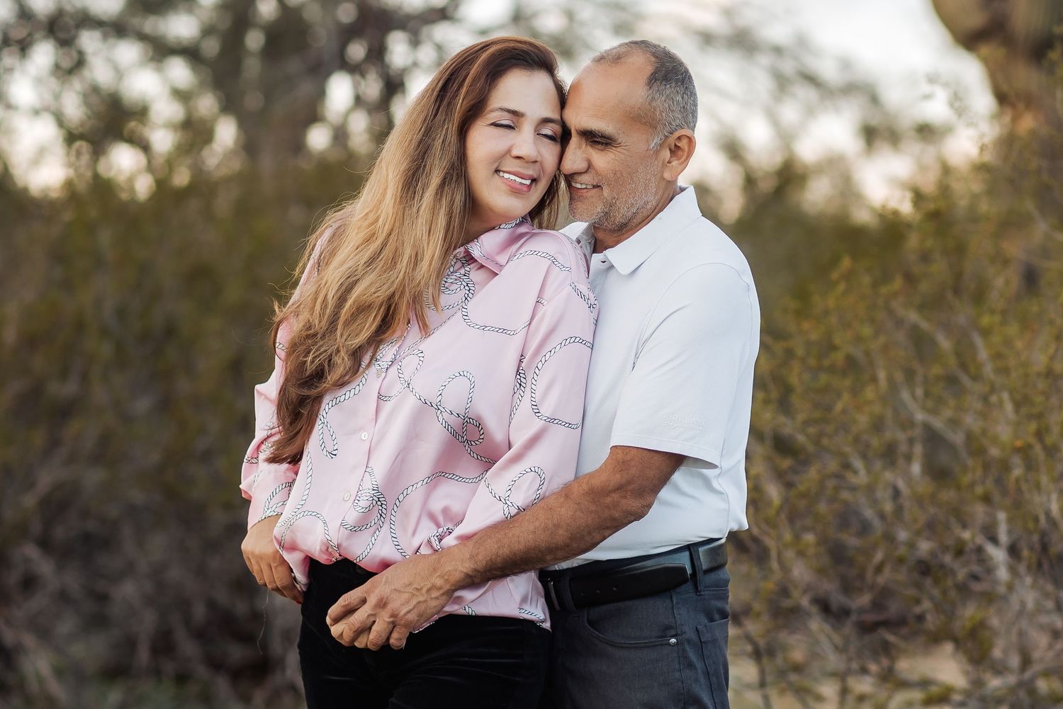 A couple shares tender moments in a golden outdoor setting during their engagement photo session.