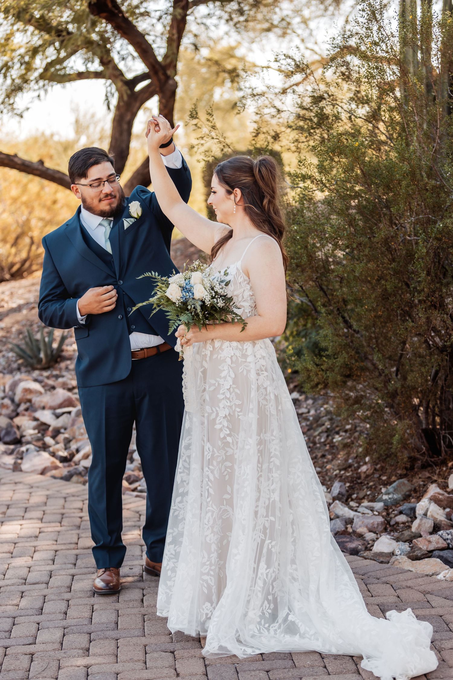 Wedding couple sharing an emotional first look moment on a brick path surrounded by desert landscaping.