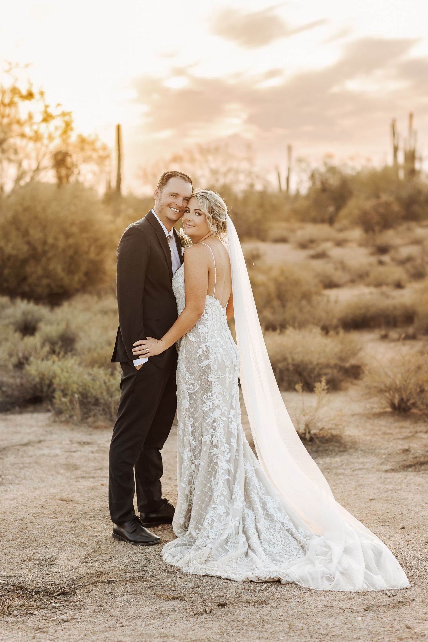 A romantic desert sunset wedding portrait with saguaro cacti in the background.