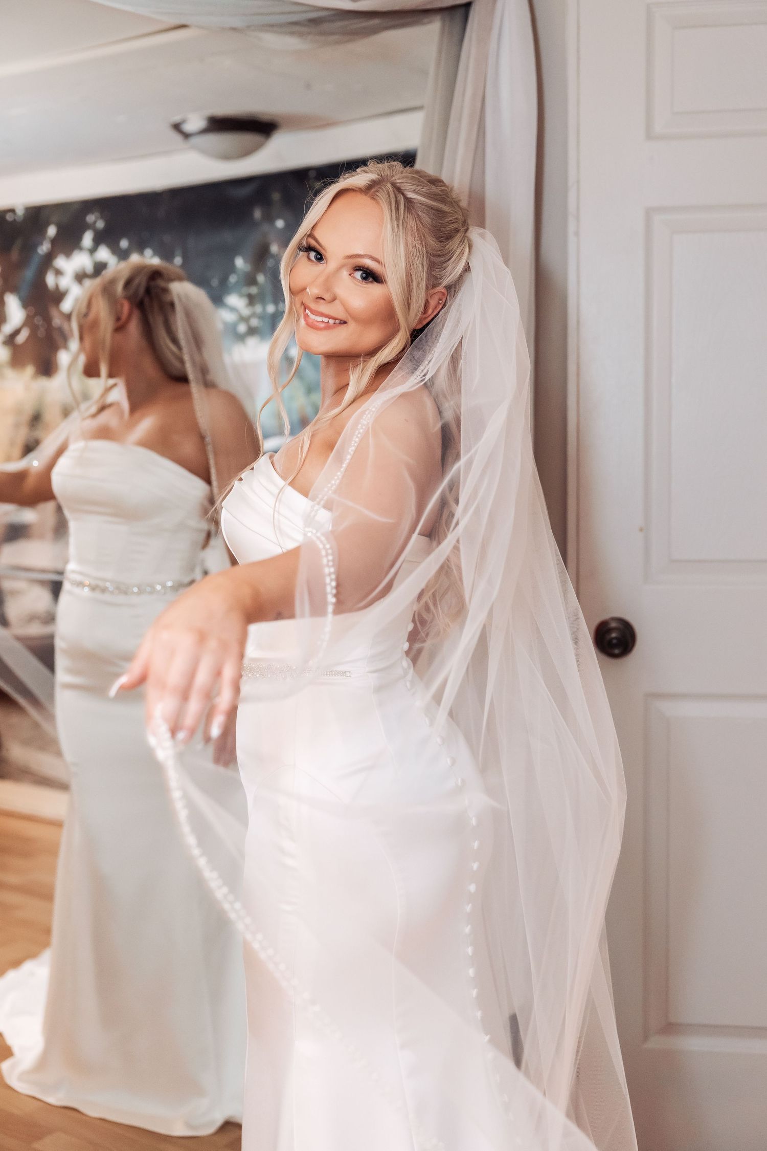 Bride in white wedding dress and veil getting ready on her special day.