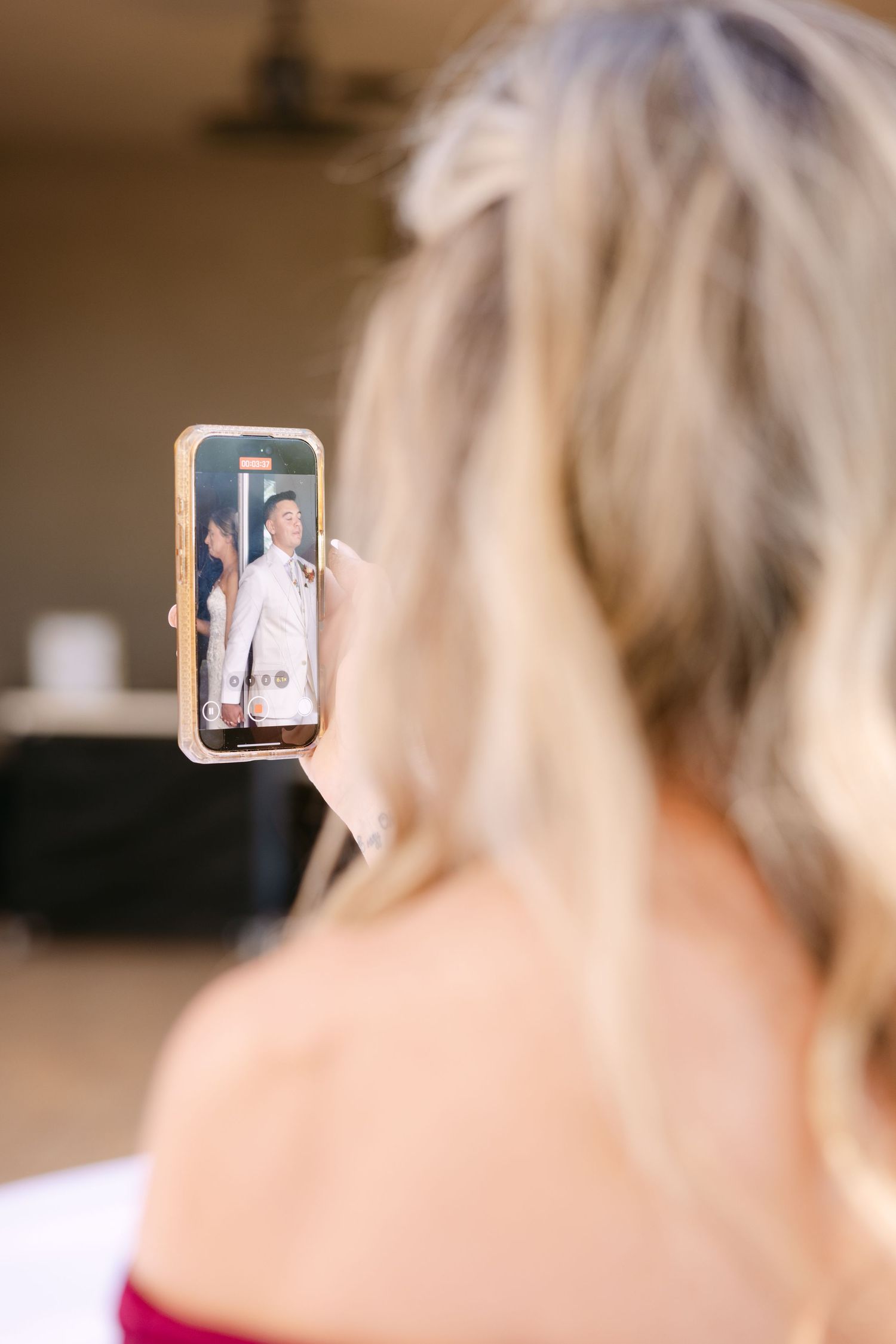A person holds up a smartphone displaying a video call screen in a home setting.