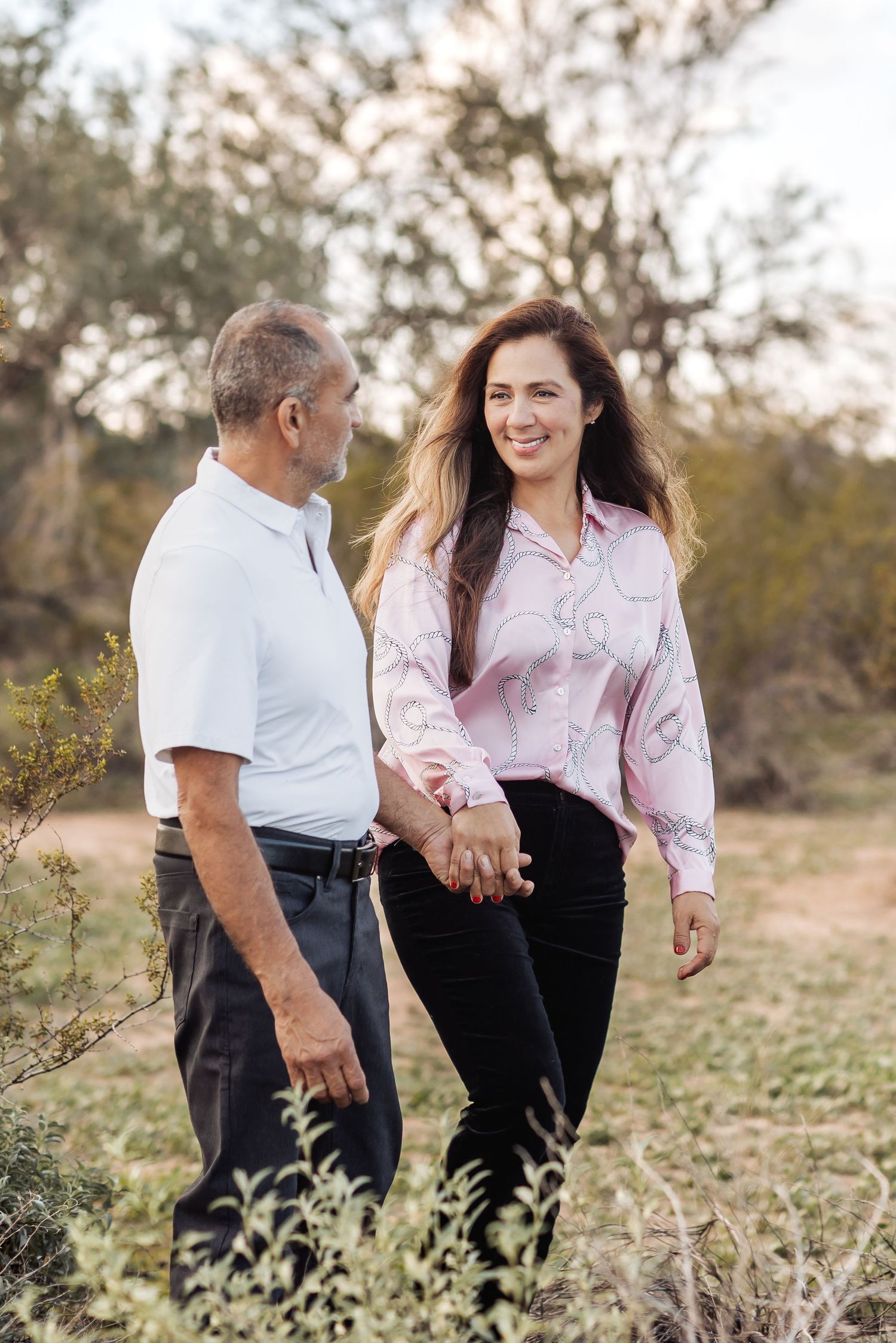 A couple walking together and sharing intimate moments in a natural outdoor setting during golden hour.
