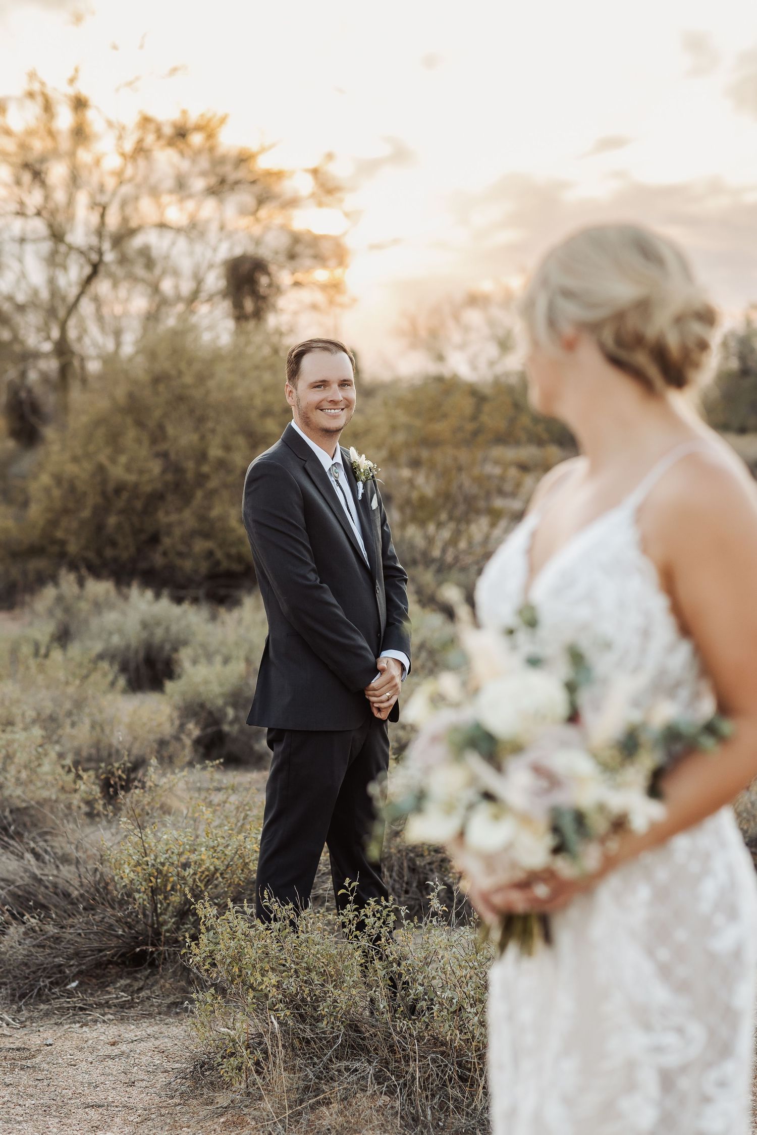 A wedding first look moment captured in a desert landscape during golden hour.