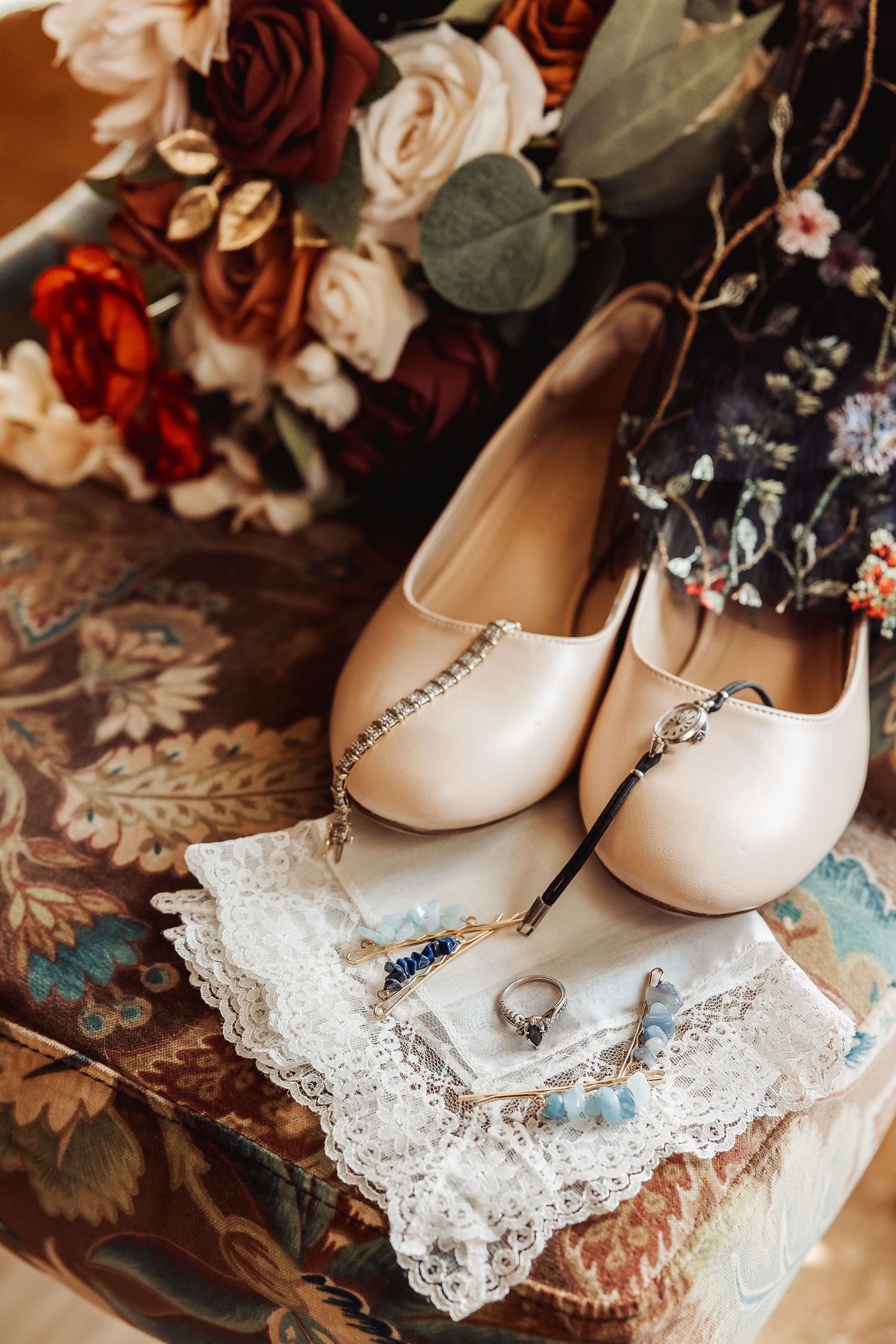 Elegant white bridal shoes resting on delicate lace against a floral backdrop.