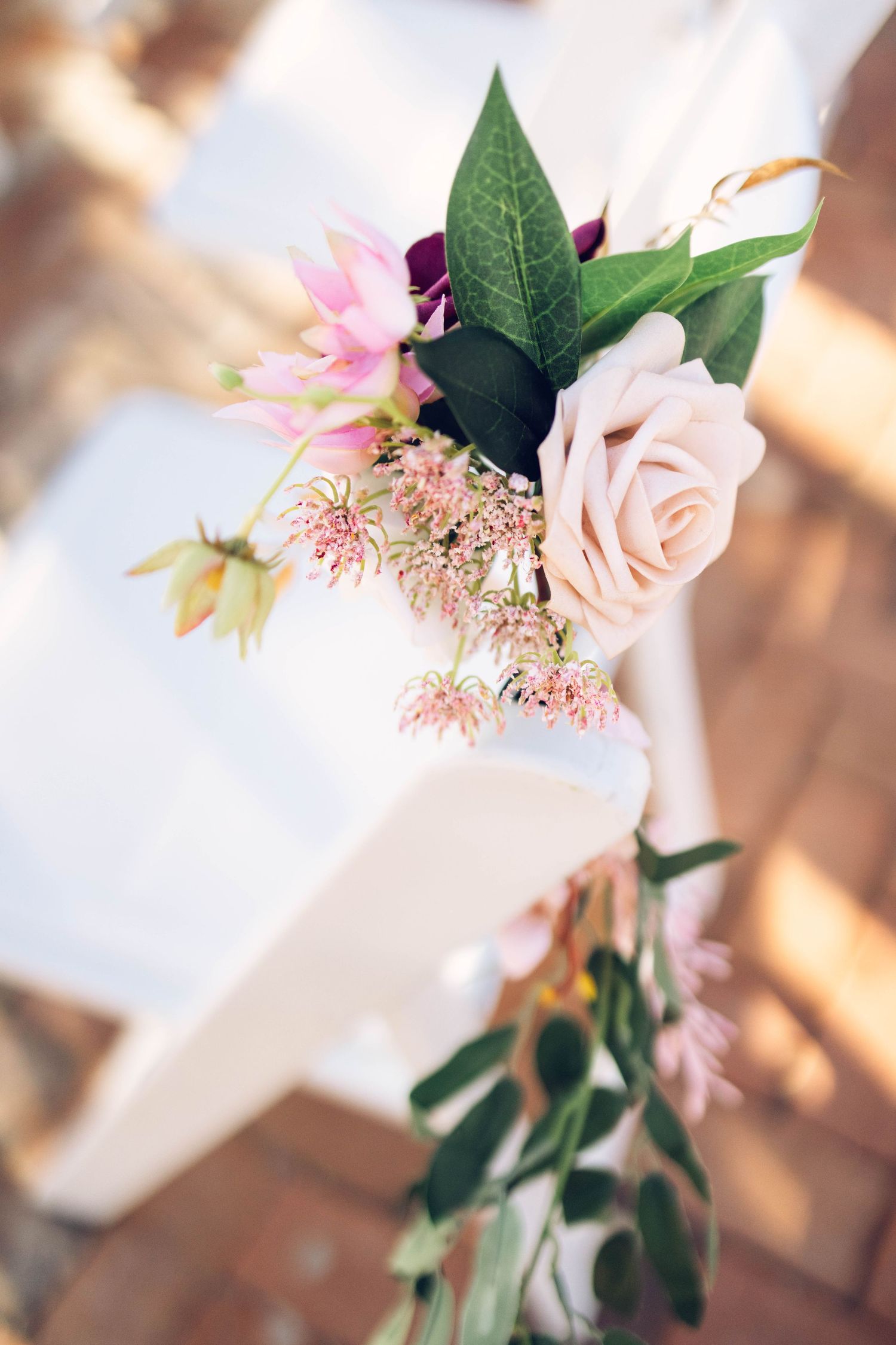 A delicate pink rose with green leaves arranged in a soft, romantic composition with blurred background.