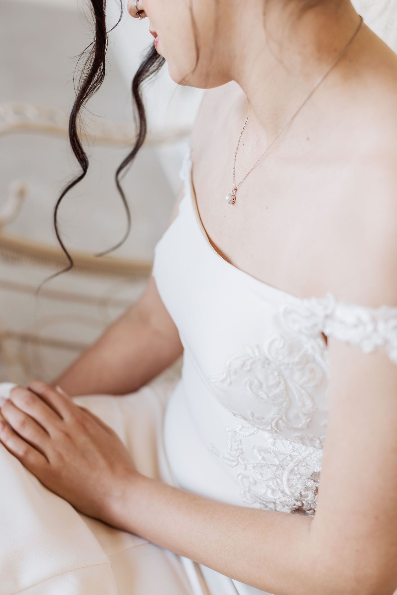 Close-up detail of a delicate lace wedding dress and dainty necklace.