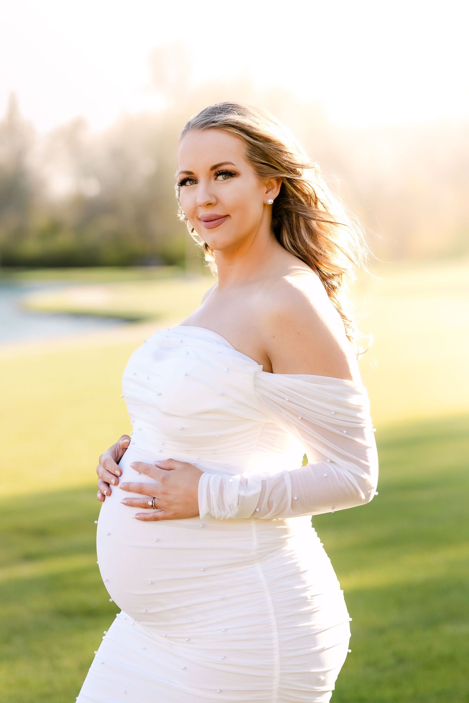 A series of maternity photos showing a woman in a white dress glowing in golden sunlight on a grassy field.