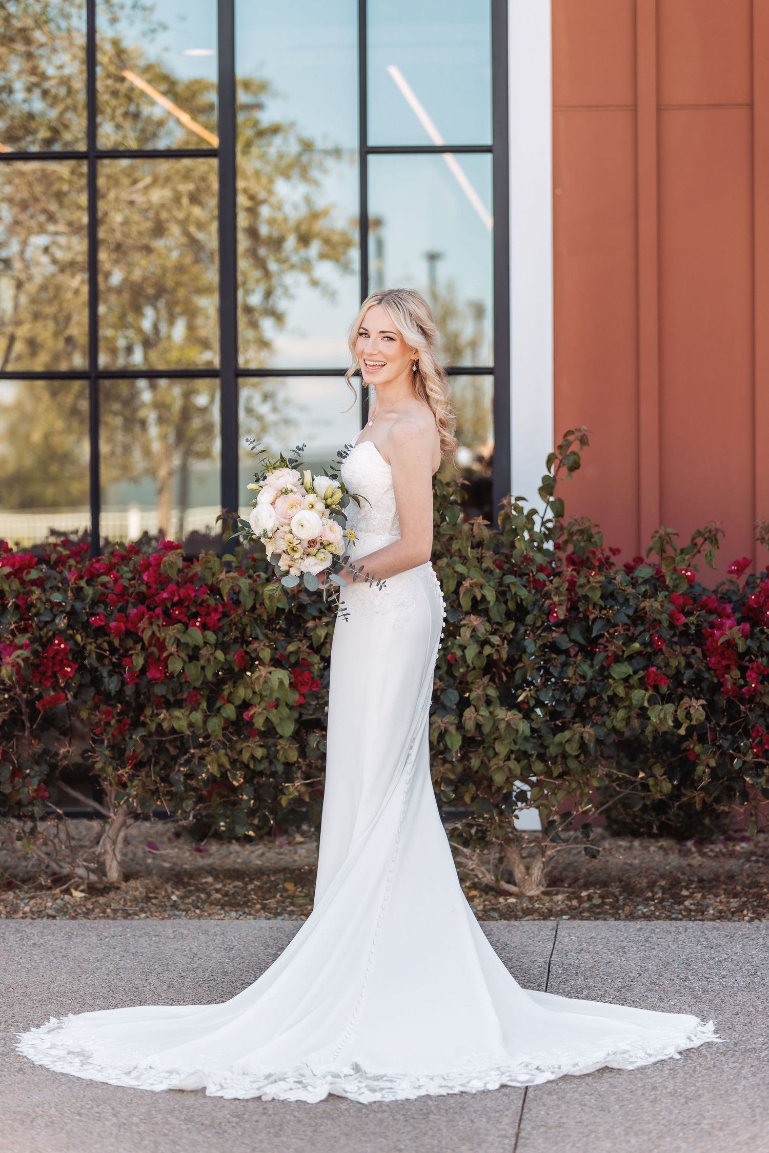 Classic bridal portraits showcasing a white lace wedding gown with cathedral train against a brick building.