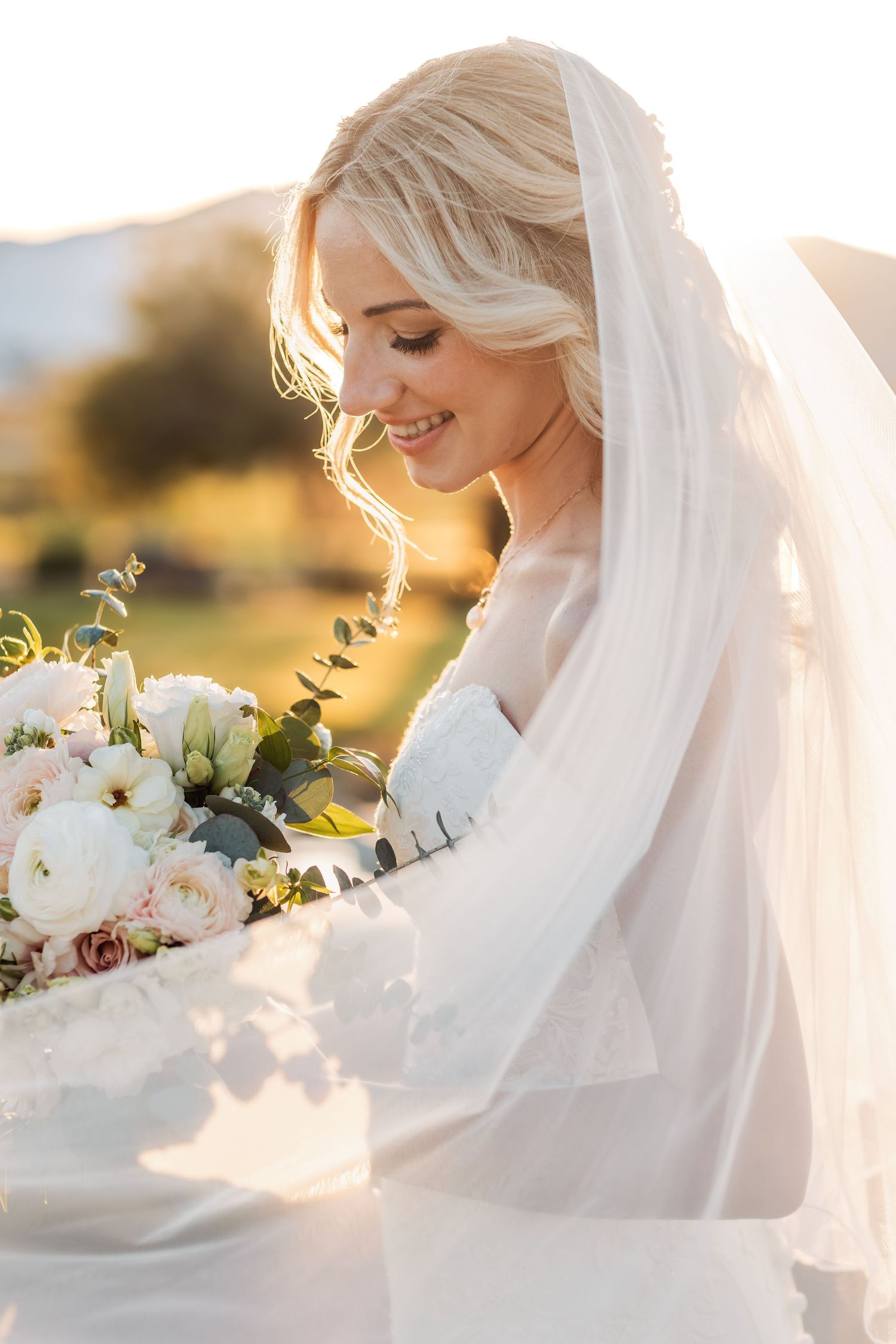 Ethereal bridal portraits at golden hour featuring white bouquet and flowing veil.