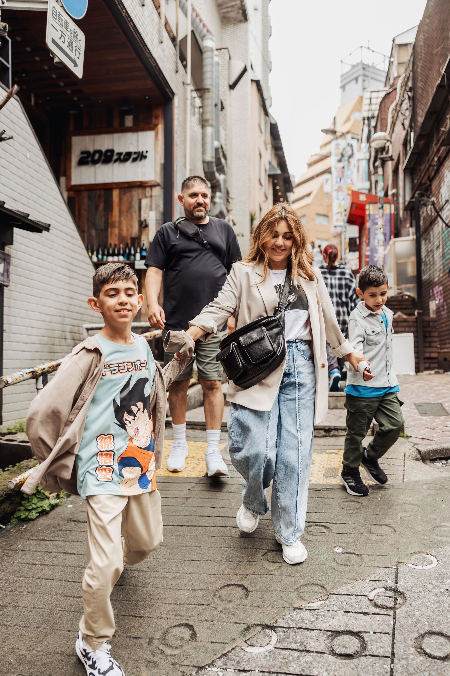 Family walking together on a narrow cobblestone street in an urban neighborhood wearing casual clothes.