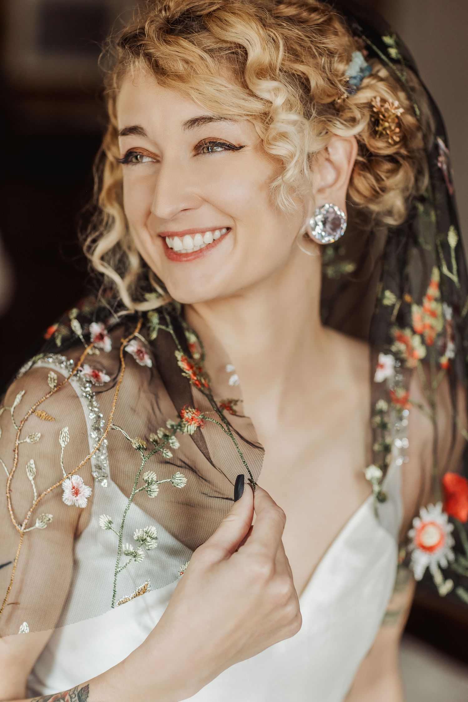Elegant bridal portrait with embroidered floral veil and sparkling jewelry.