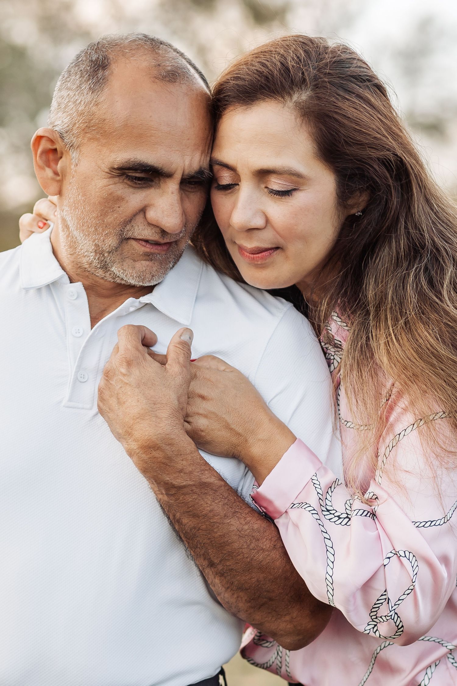 A romantic couple in white and pink outfits share tender moments in a series of intimate close-up photographs.