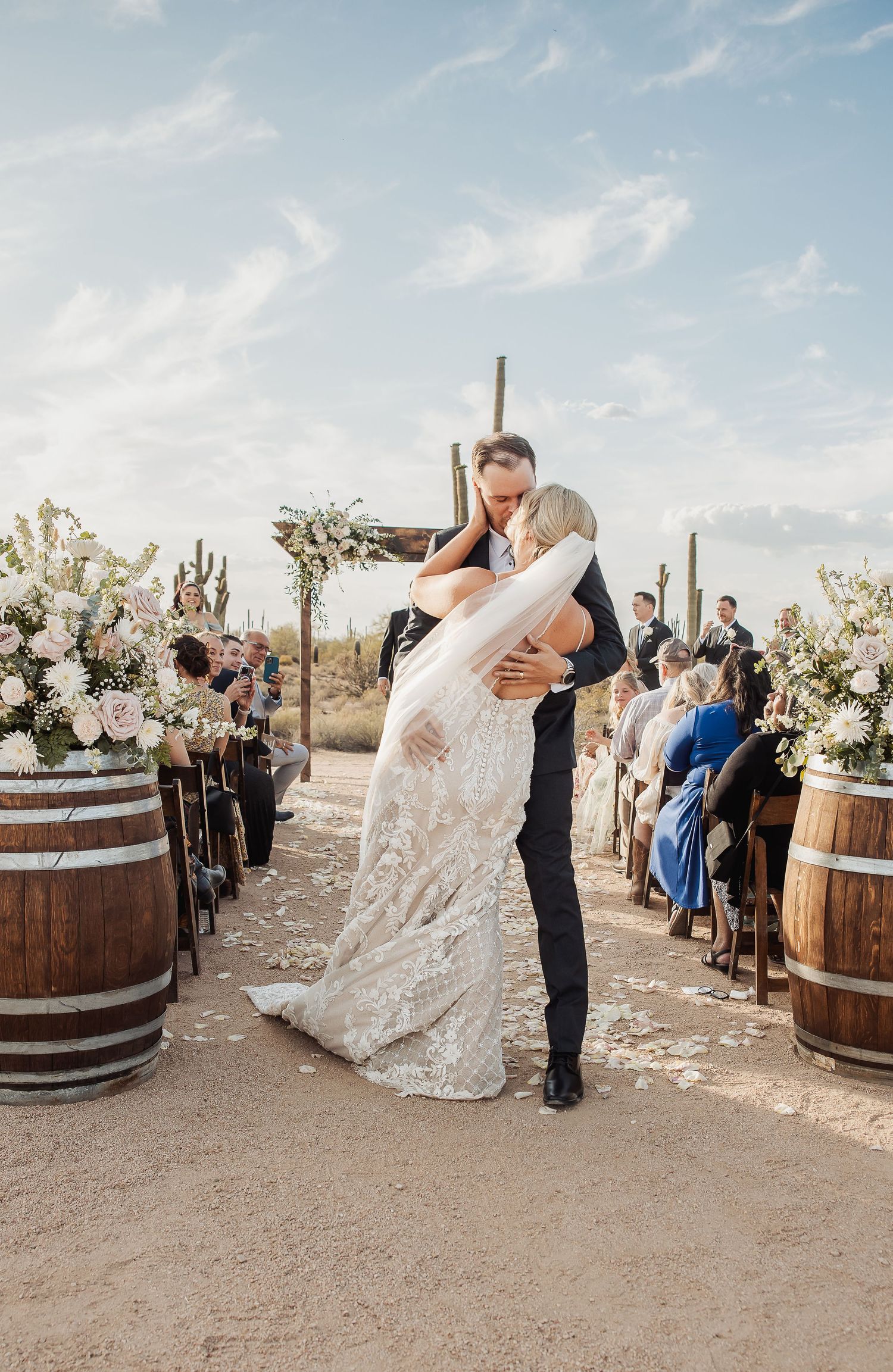Romantic outdoor desert wedding ceremony with barrel decor during sunset showing multiple angles of a couple's embracing dance.