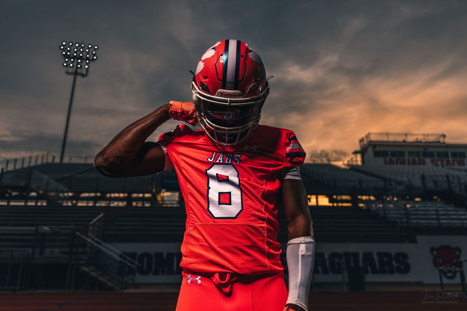 Football player number 6 in red Jaguars uniform posing at stadium during sunset.