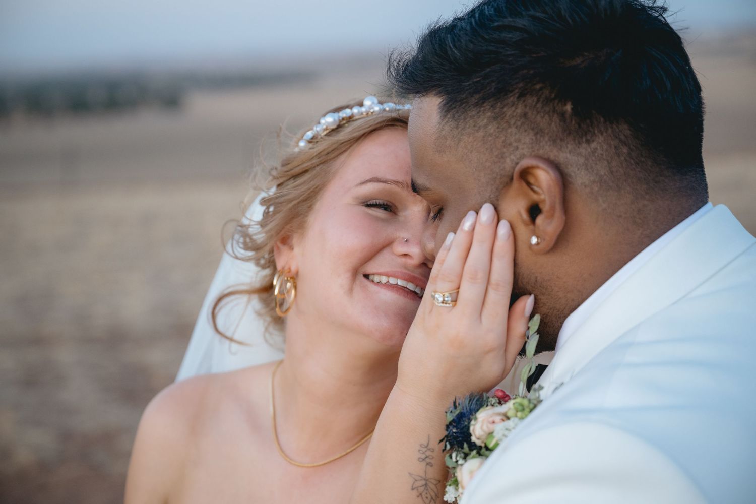 A bride and groom share an intimate moment during their wedding photoshoot on a beach.