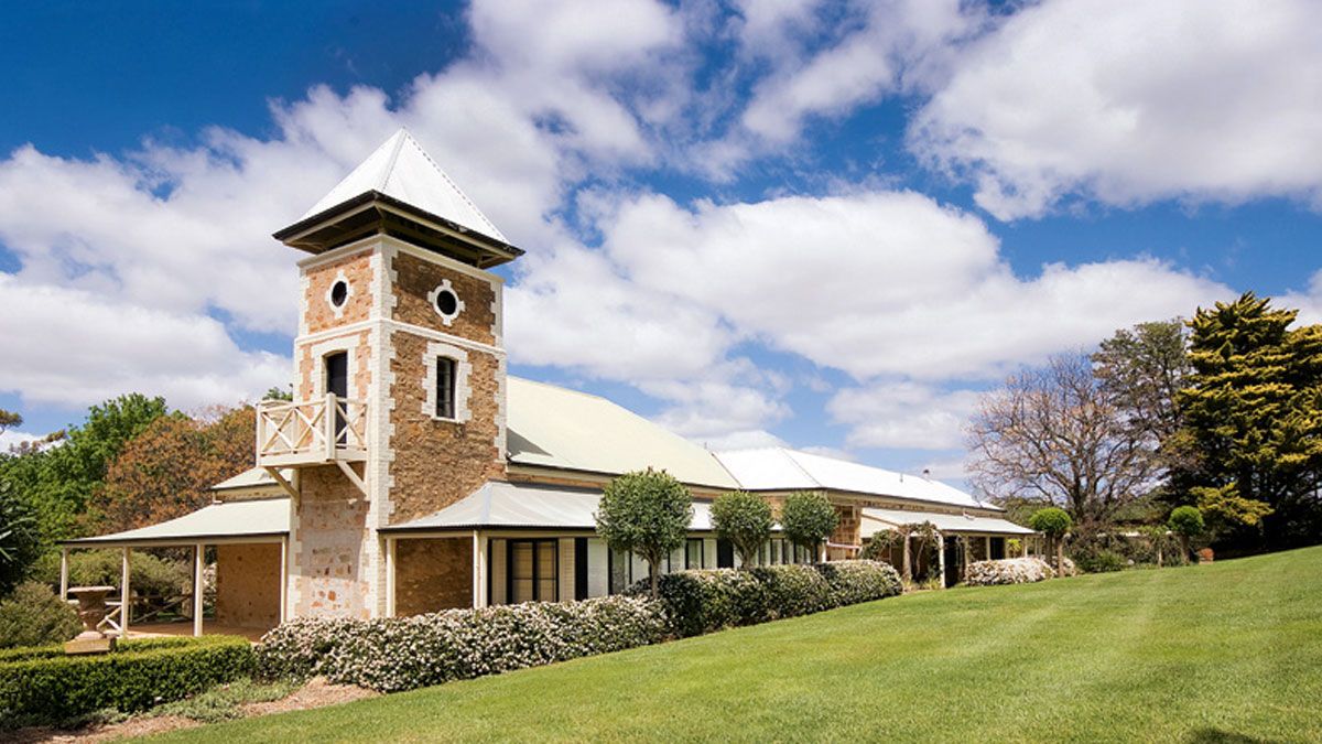 A panoramic view of a golf course clubhouse with a clock tower against a blue sky with white clouds.