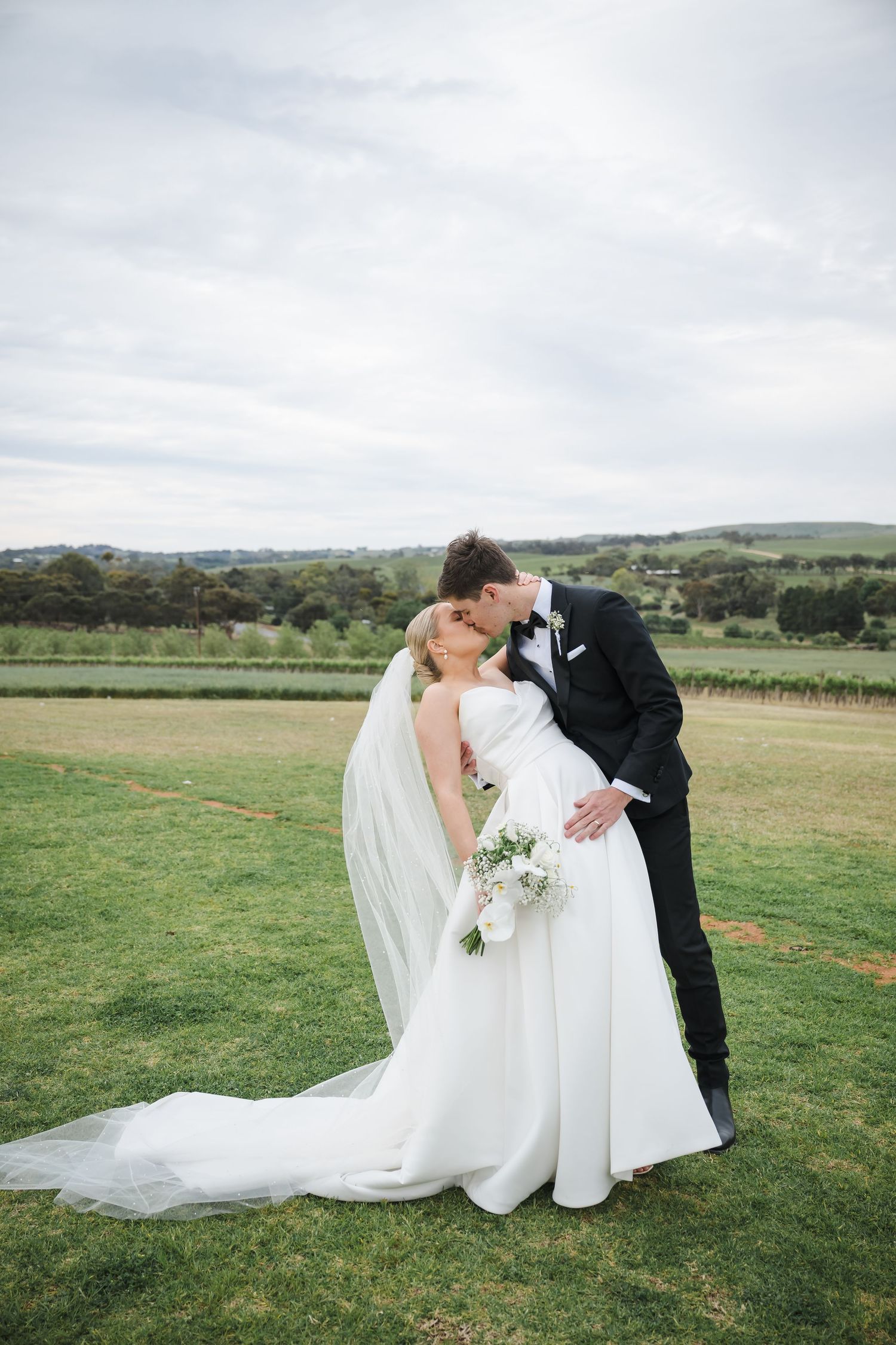A romantic wedding couple shares an intimate moment in a scenic vineyard setting during their outdoor photo session.