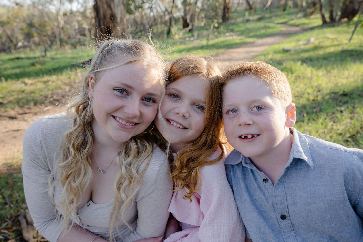 A series of outdoor family portrait photos taken in a grassy park setting with natural lighting and warm expressions.