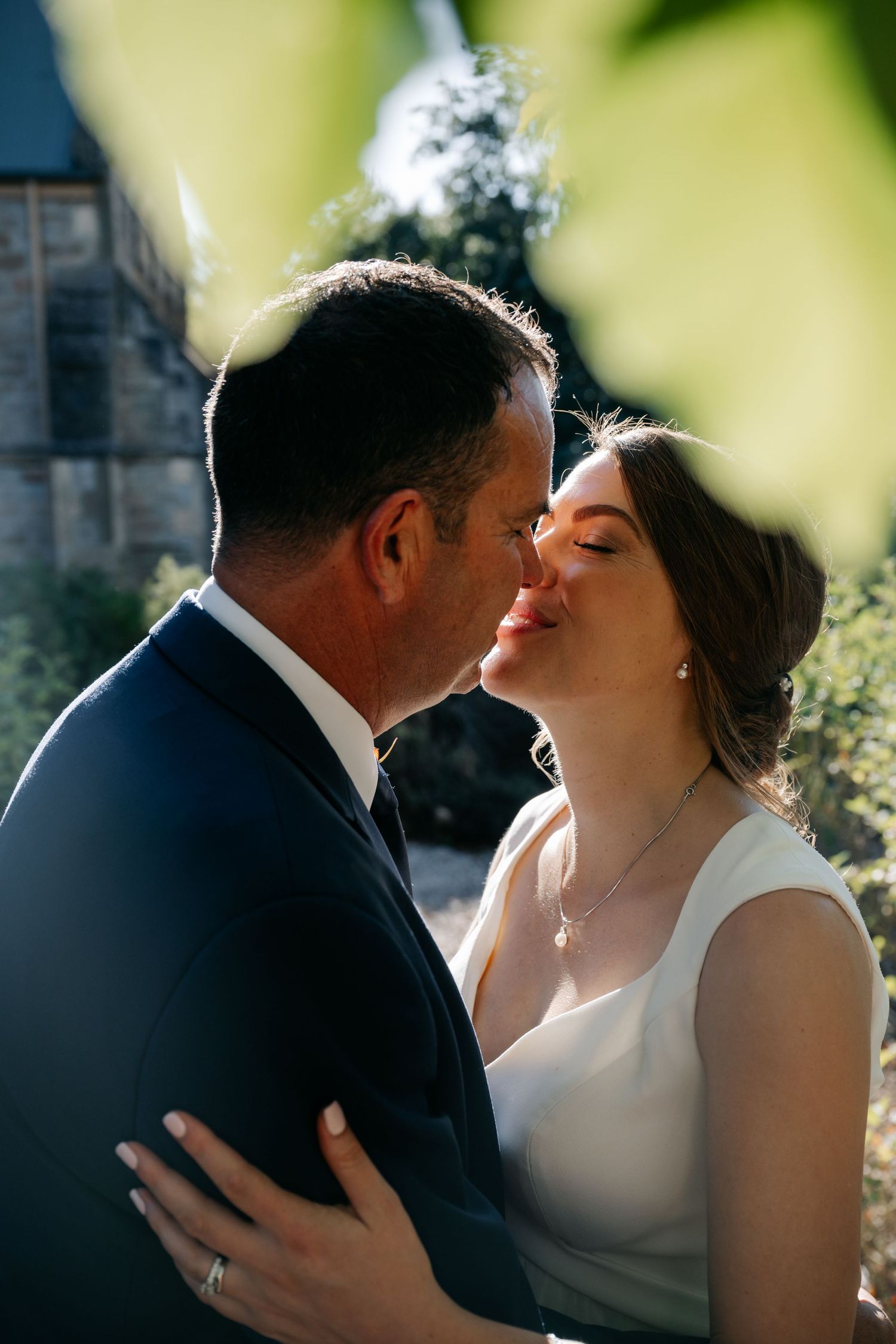 A romantic wedding couple shares an intimate kiss in a series of five candid photos outdoors.
