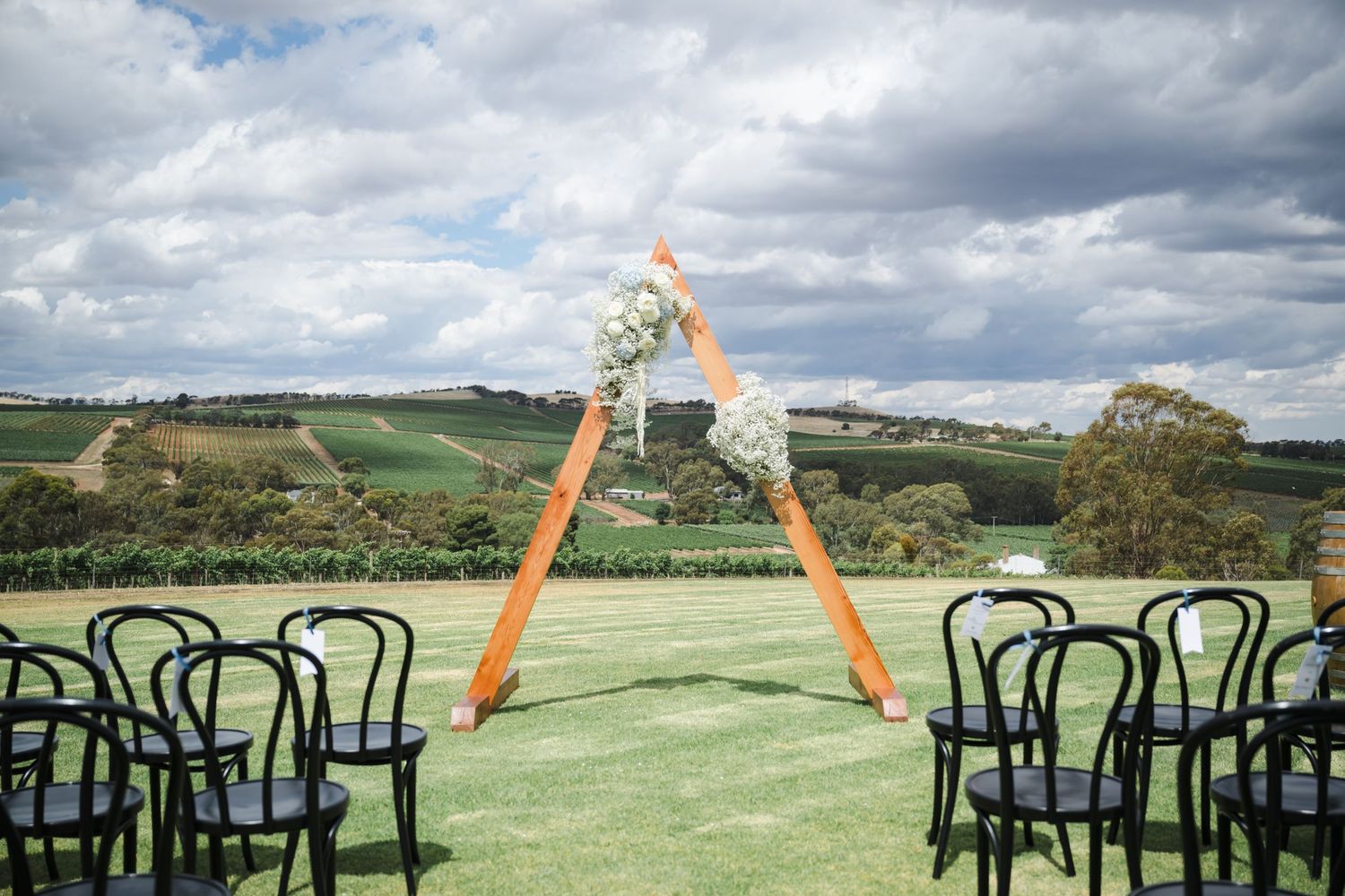 Black chairs arranged on a grassy hilltop overlooking a scenic countryside landscape under dramatic cloudy skies.