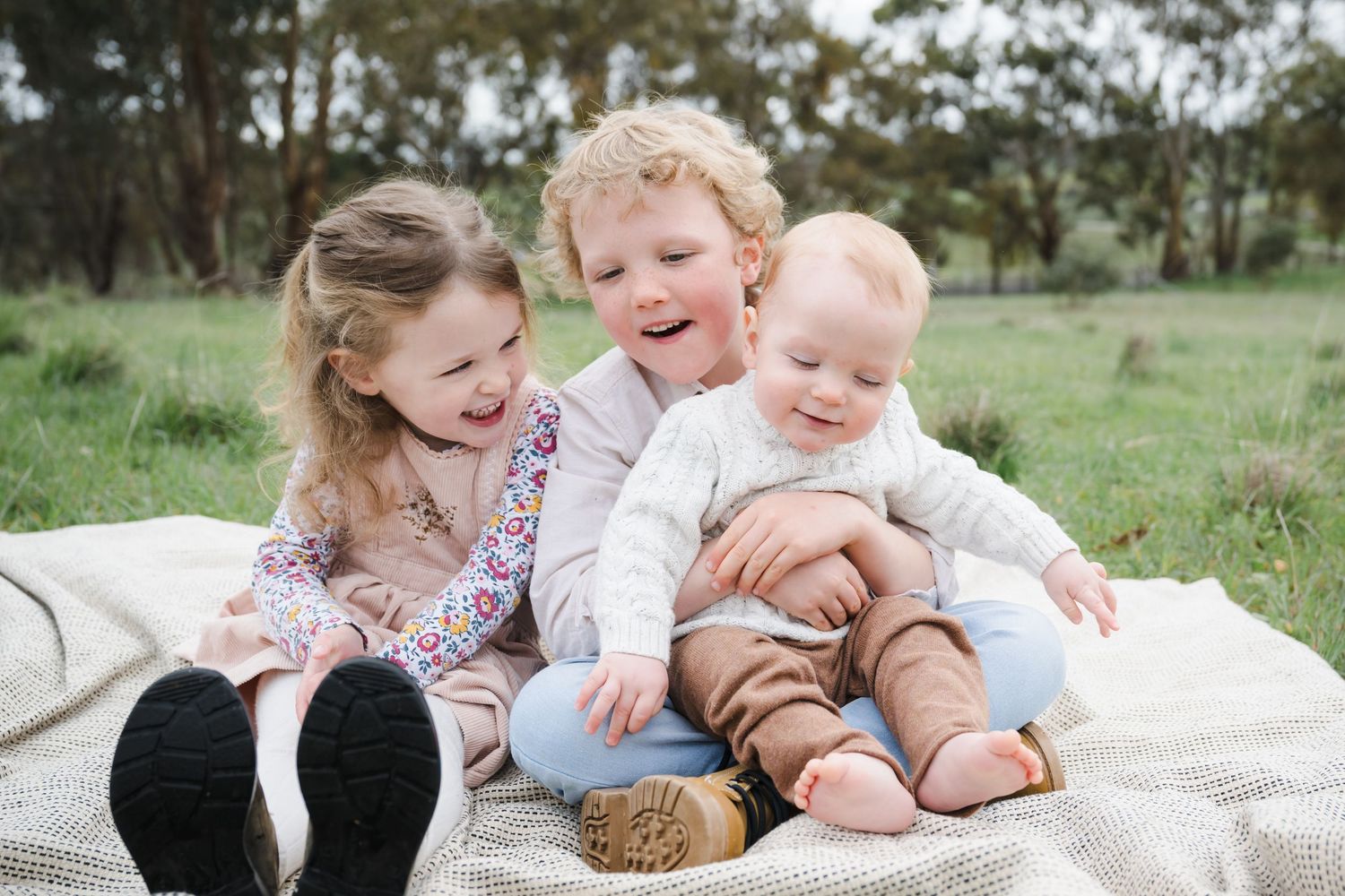 A series of outdoor family photos showing tender moments between parents and children on a grassy field during a photo session.