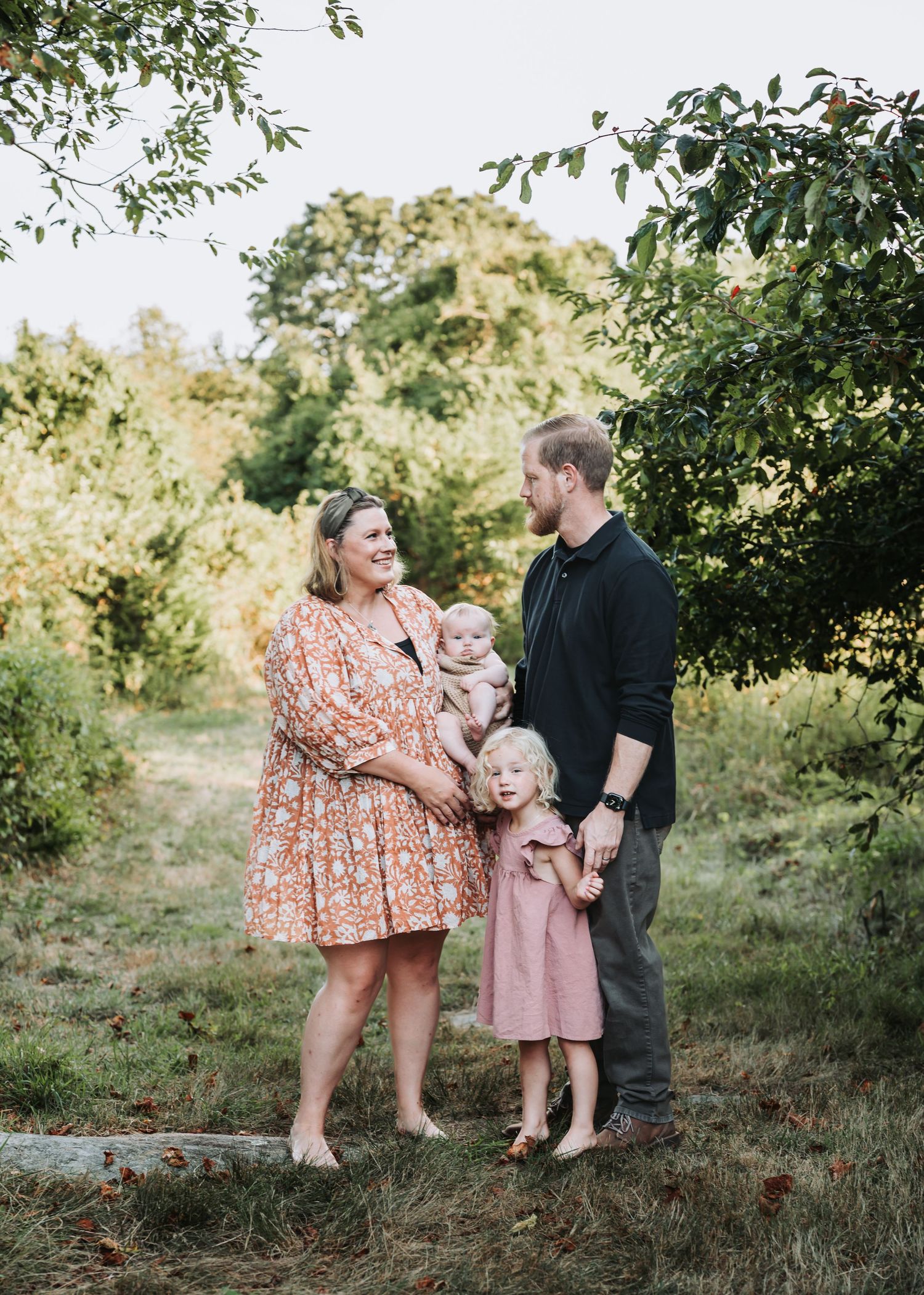 A family shares a tender moment together in an outdoor garden setting during a photo session.