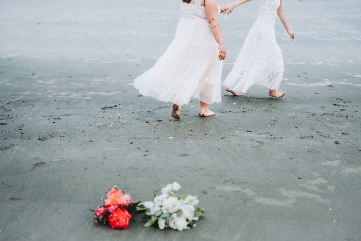 A person in a flowing white dress walks barefoot along a misty beach leaving footprints in the sand.