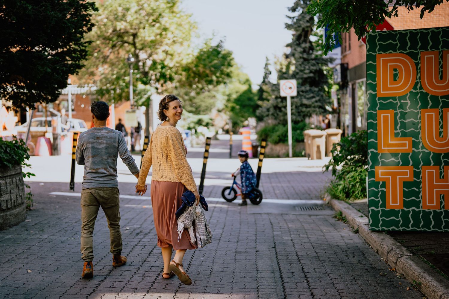 People strolling down a charming cobblestone street lined with historic buildings on a sunny afternoon.