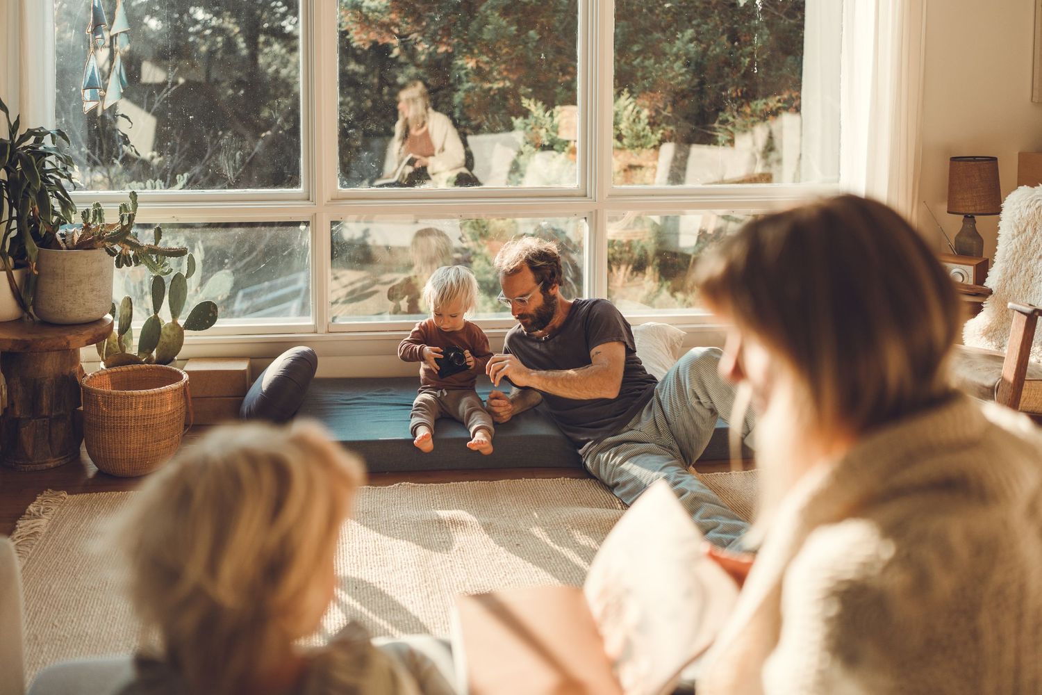 Warm morning sunlight streams through windows as family relaxes together on floor cushions.