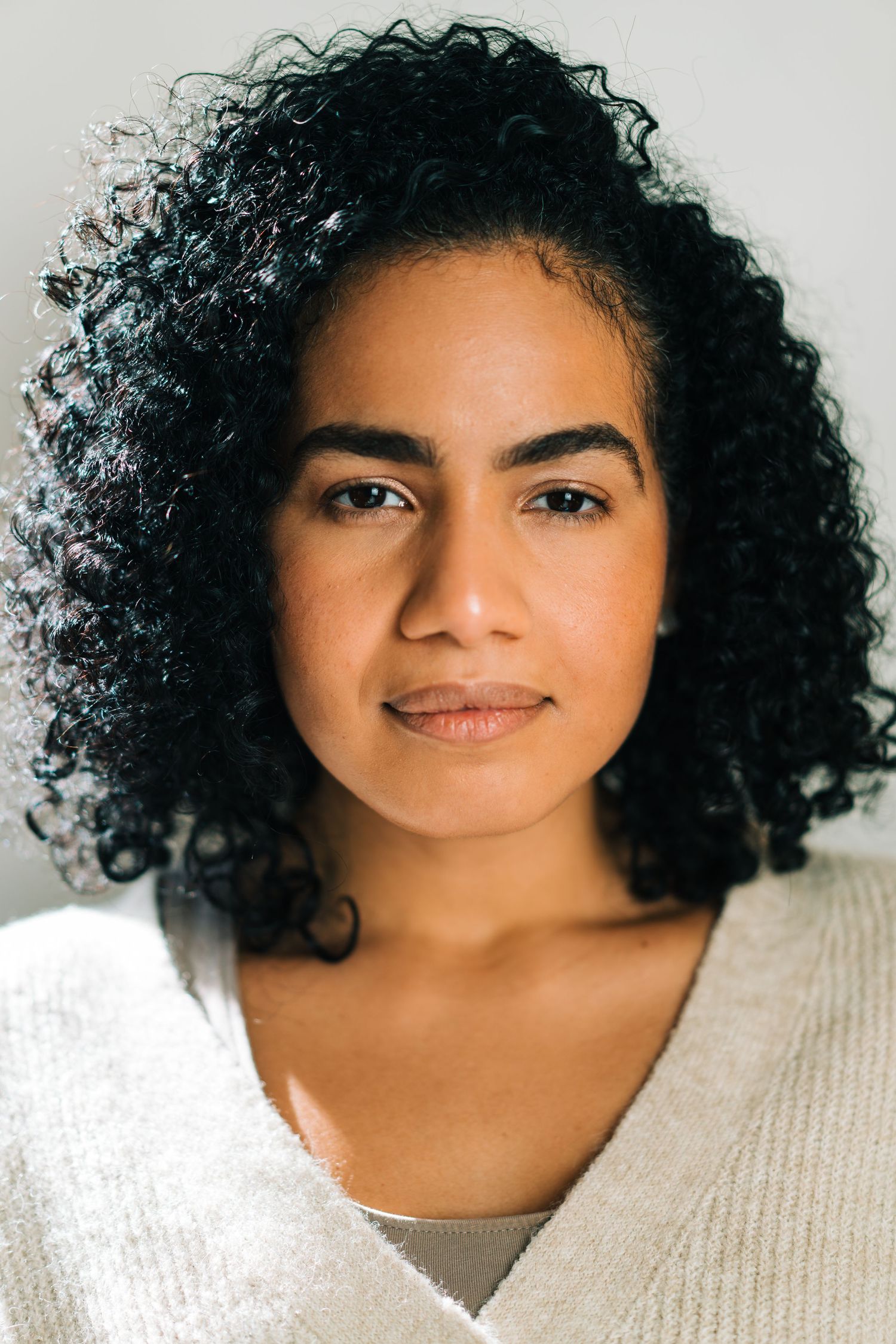 Portrait showing natural curly hair against light background.