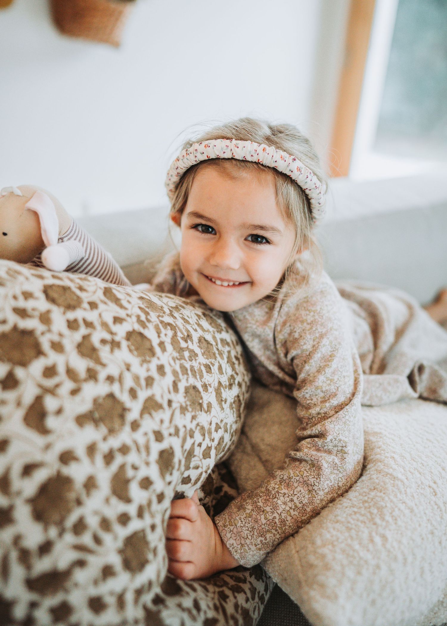 A cozy snuggling moment on white bedding with soft beige tones.