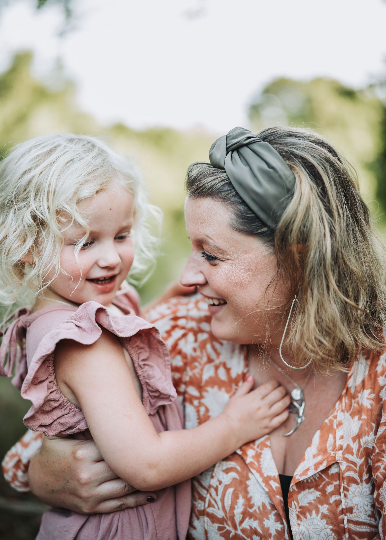 Sweet candid moment shared between parent and child showing pure joy and laughter while embracing outdoors.