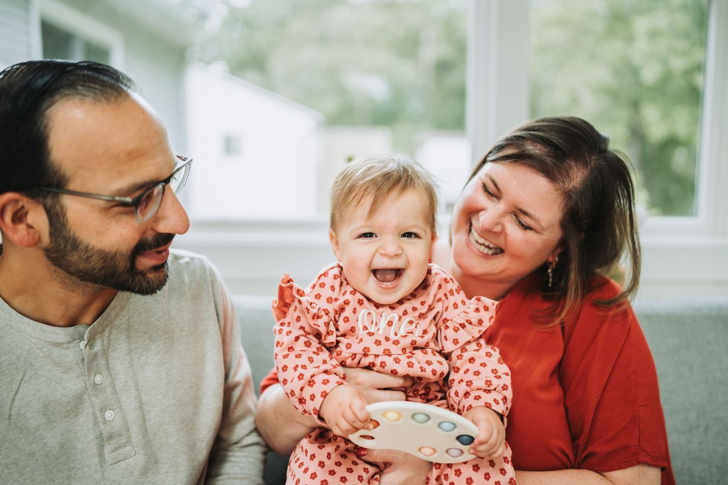 Family enjoying tender moments together on a couch in a bright living room.