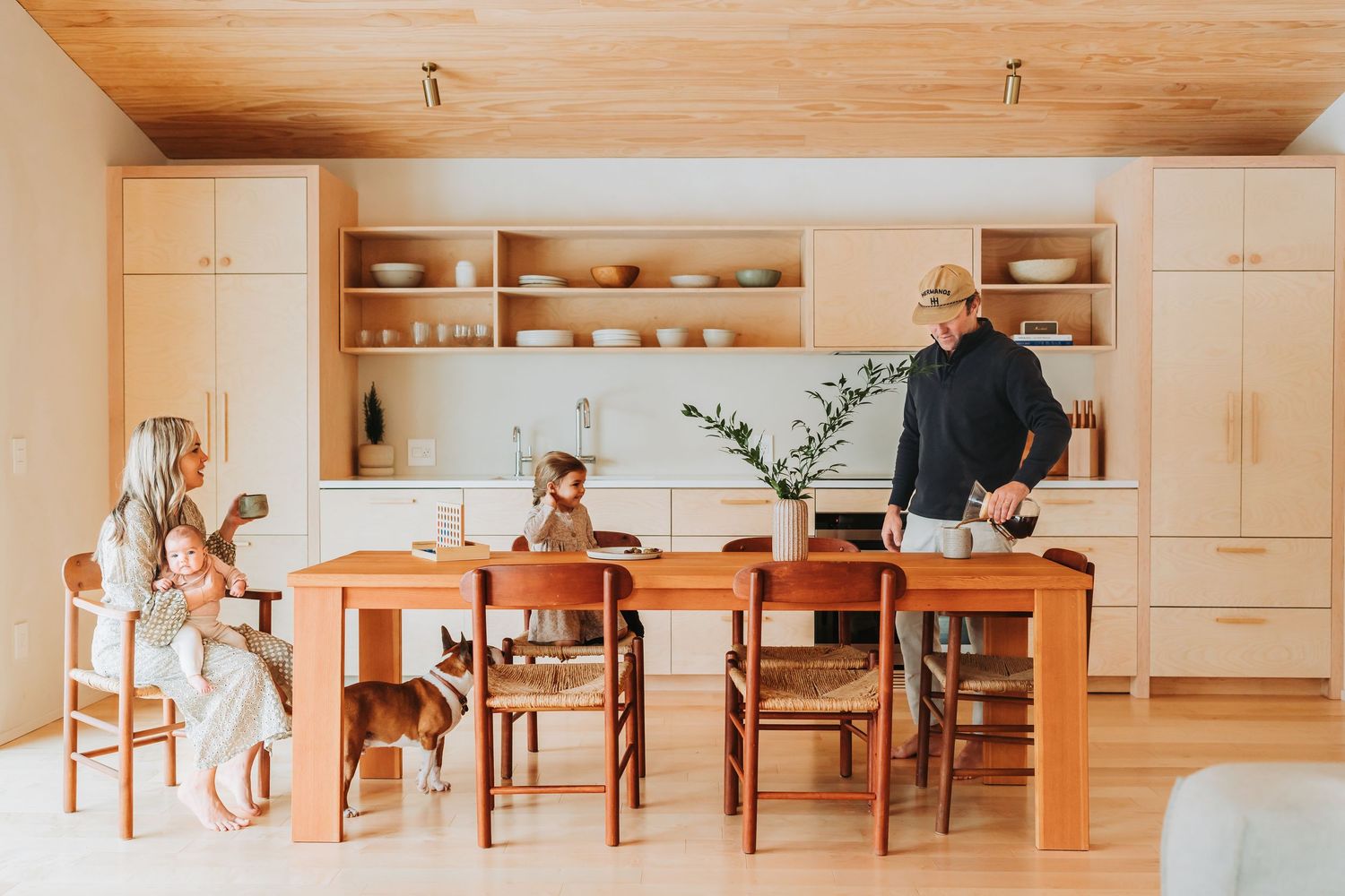 A modern spacious dining room with wood finishes features multiple tables arranged in a long row under bright lighting.