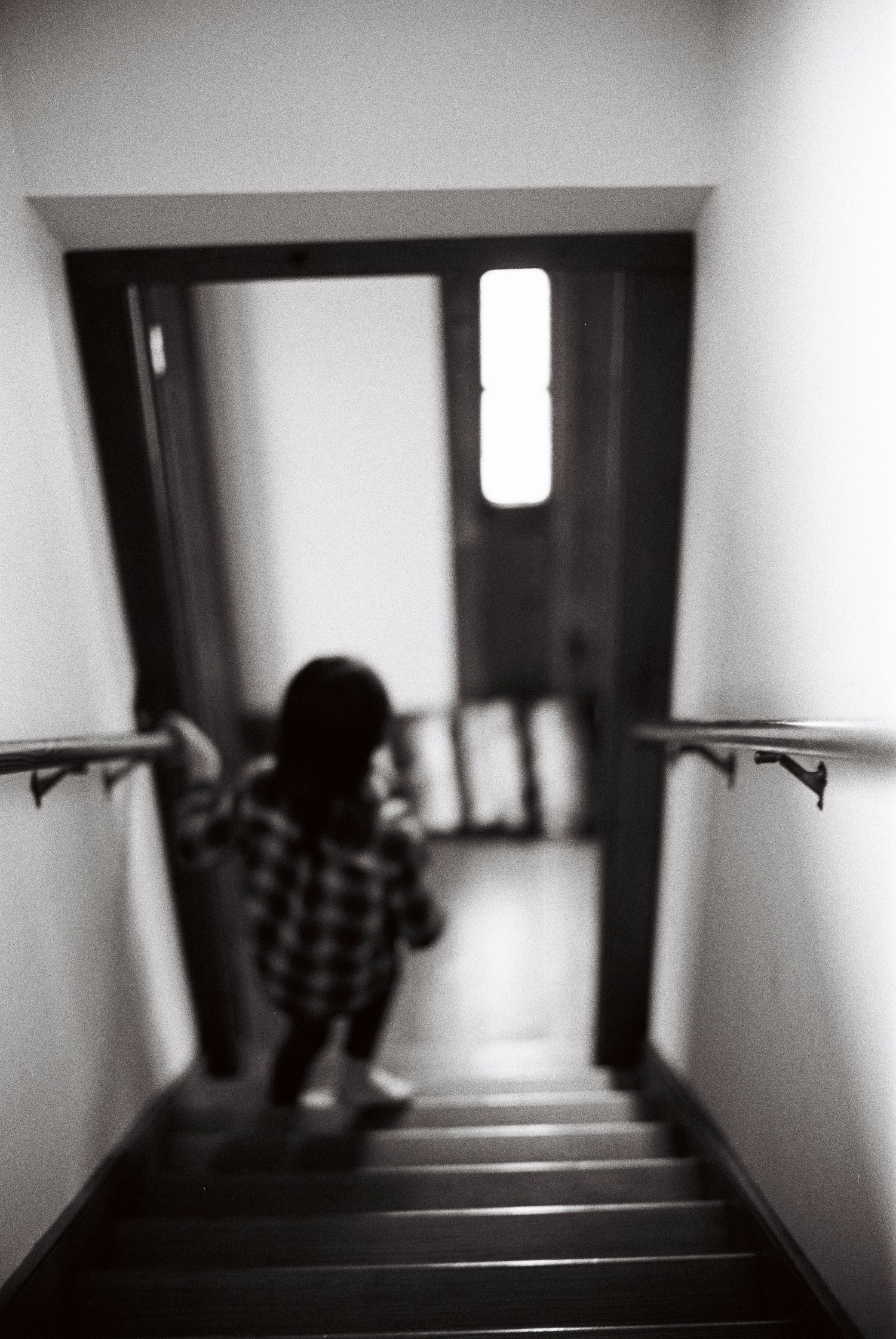 A dark figure ascends a dimly lit staircase in four sequential frames creating an eerie atmosphere.