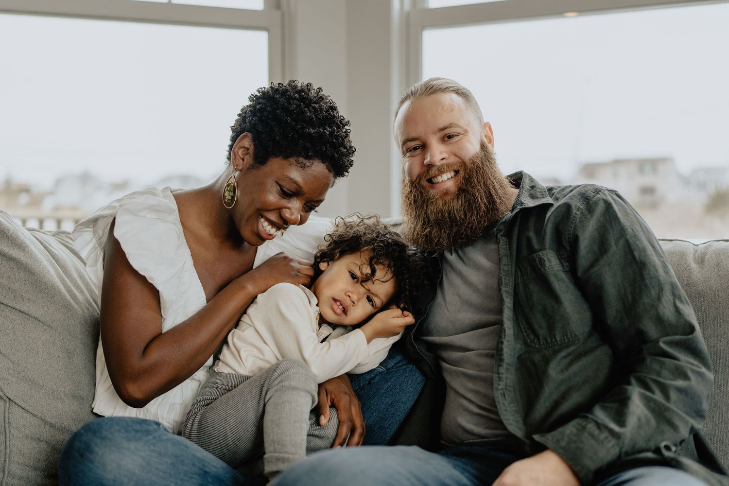 Loving family sharing a tender moment together while relaxing on a gray couch.