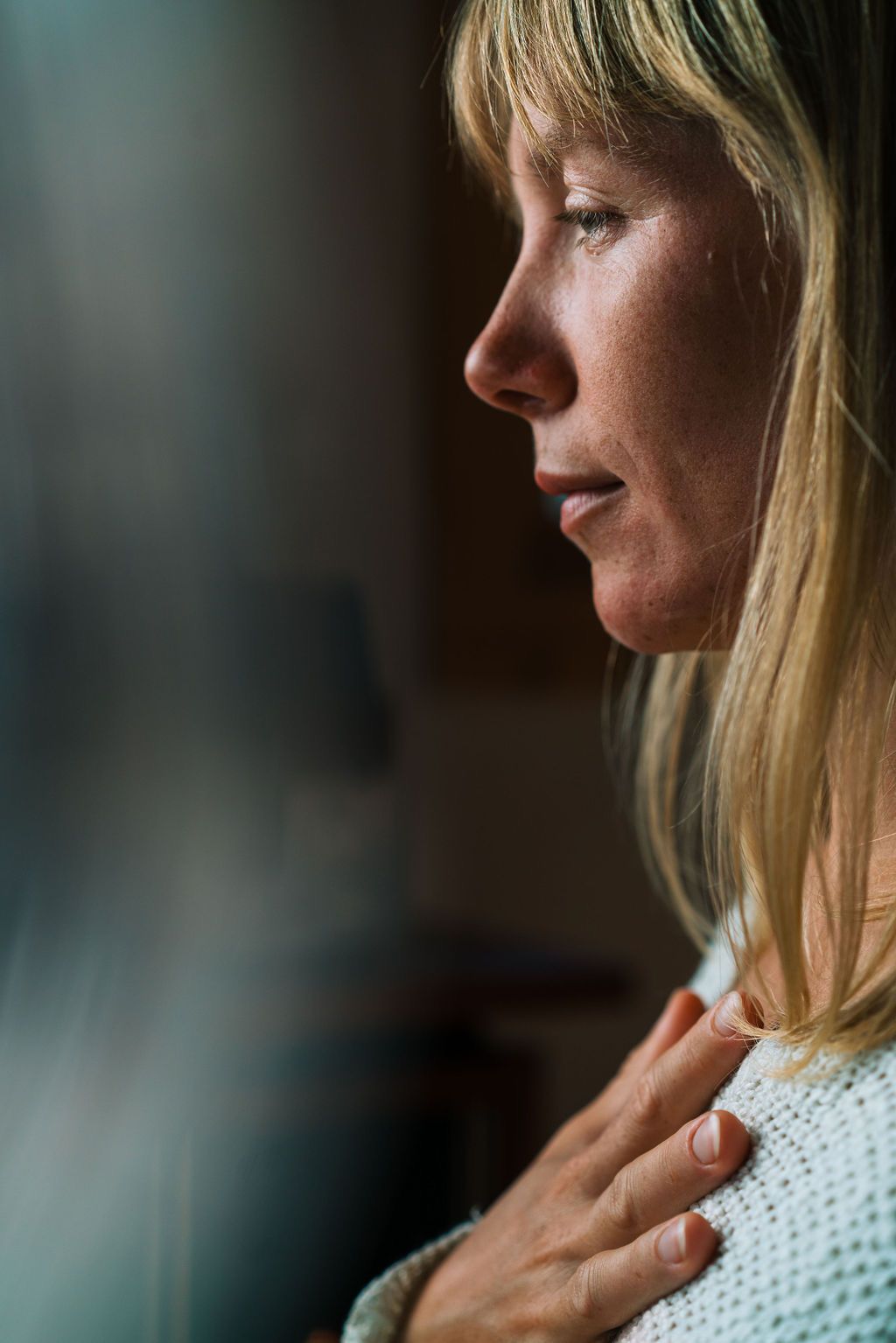 A series of profile shots showing a person in a white knit sweater against a dark background.