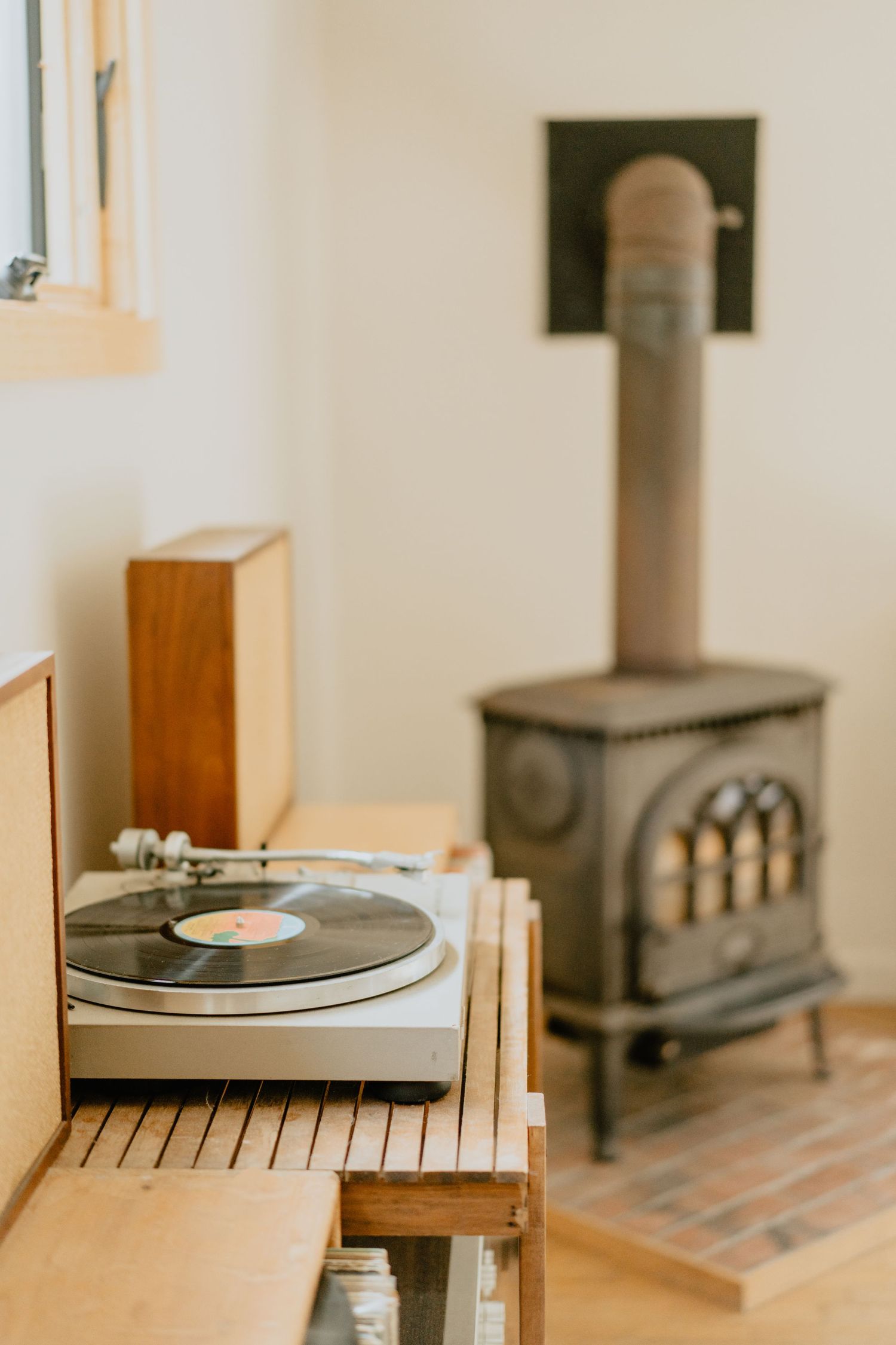 Vintage turntable and record player next to cast iron wood stove in minimalist room.