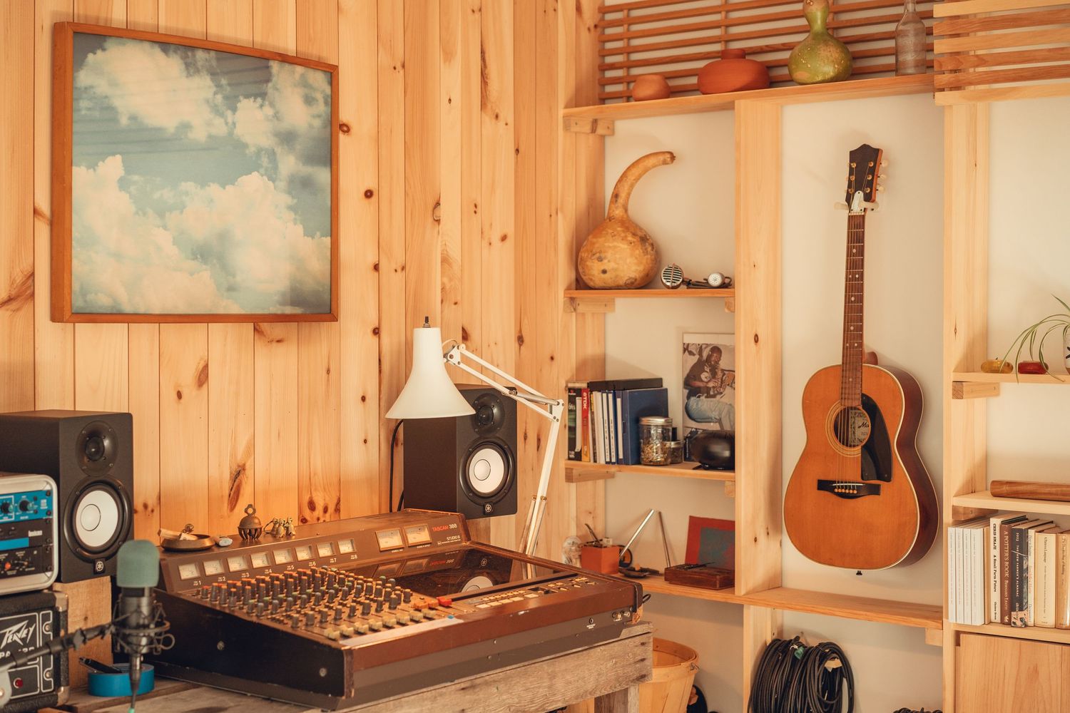Vintage-style recording studio with wooden panels, mixing console, and acoustic guitar display.