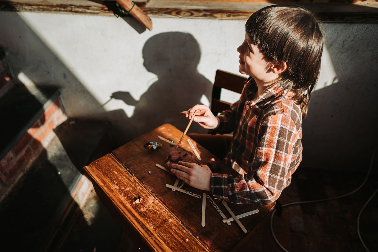 Person inspecting fine details of wooden furniture with craftsman tools during restoration or repair.