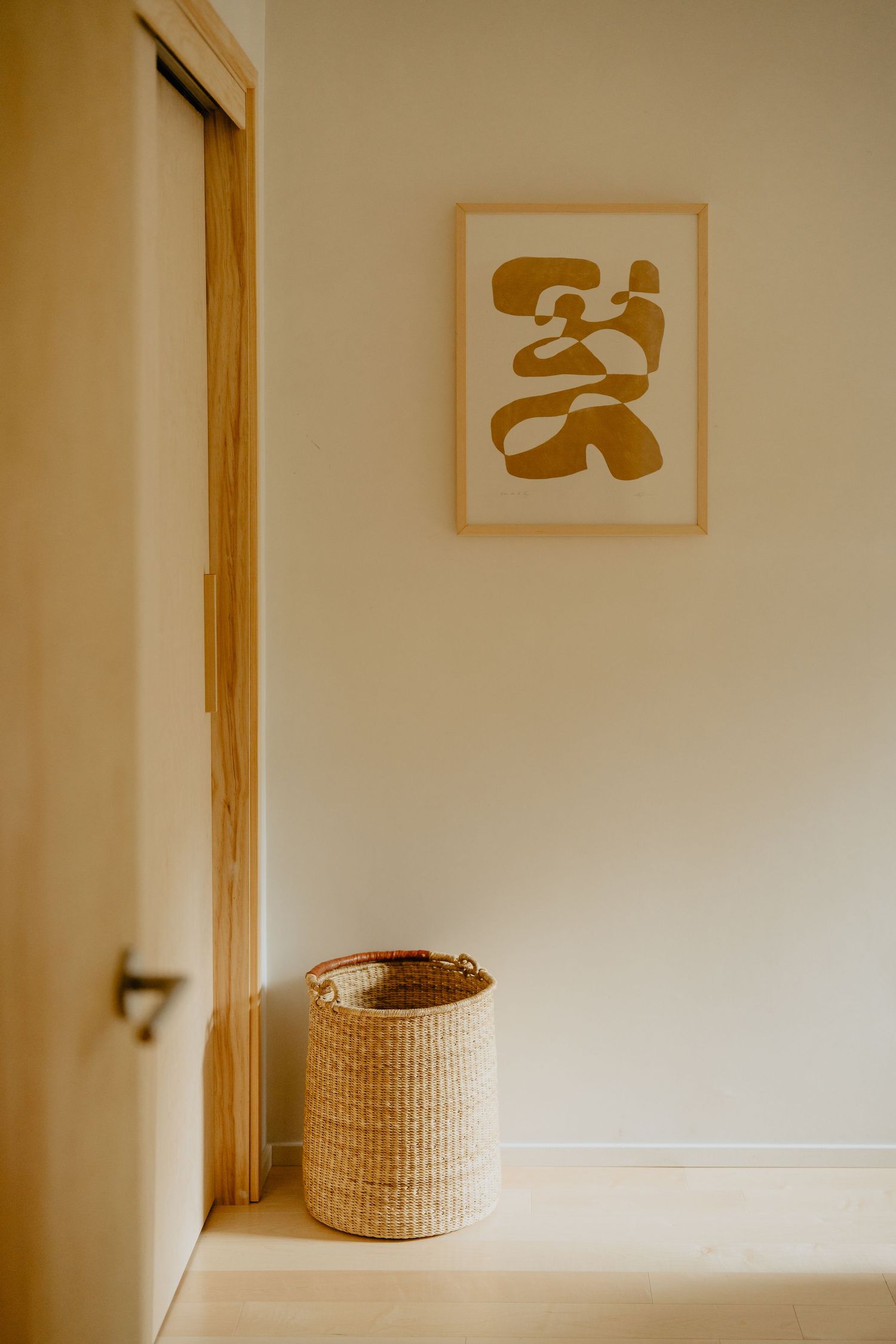 Minimalist hallway with abstract wall art and woven basket.