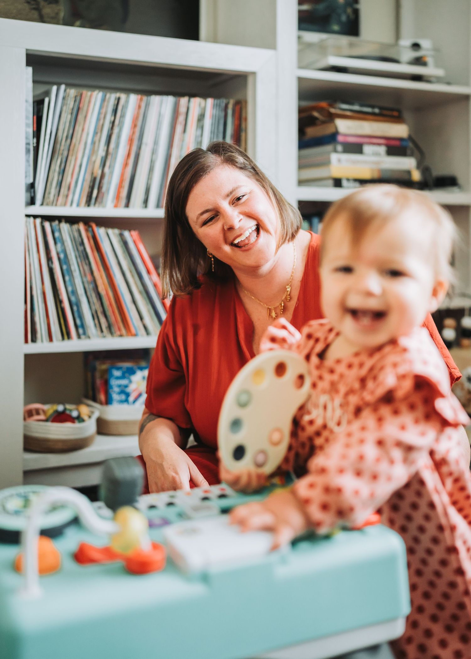 A joyful moment of play and learning at a table with bookshelves in the background.