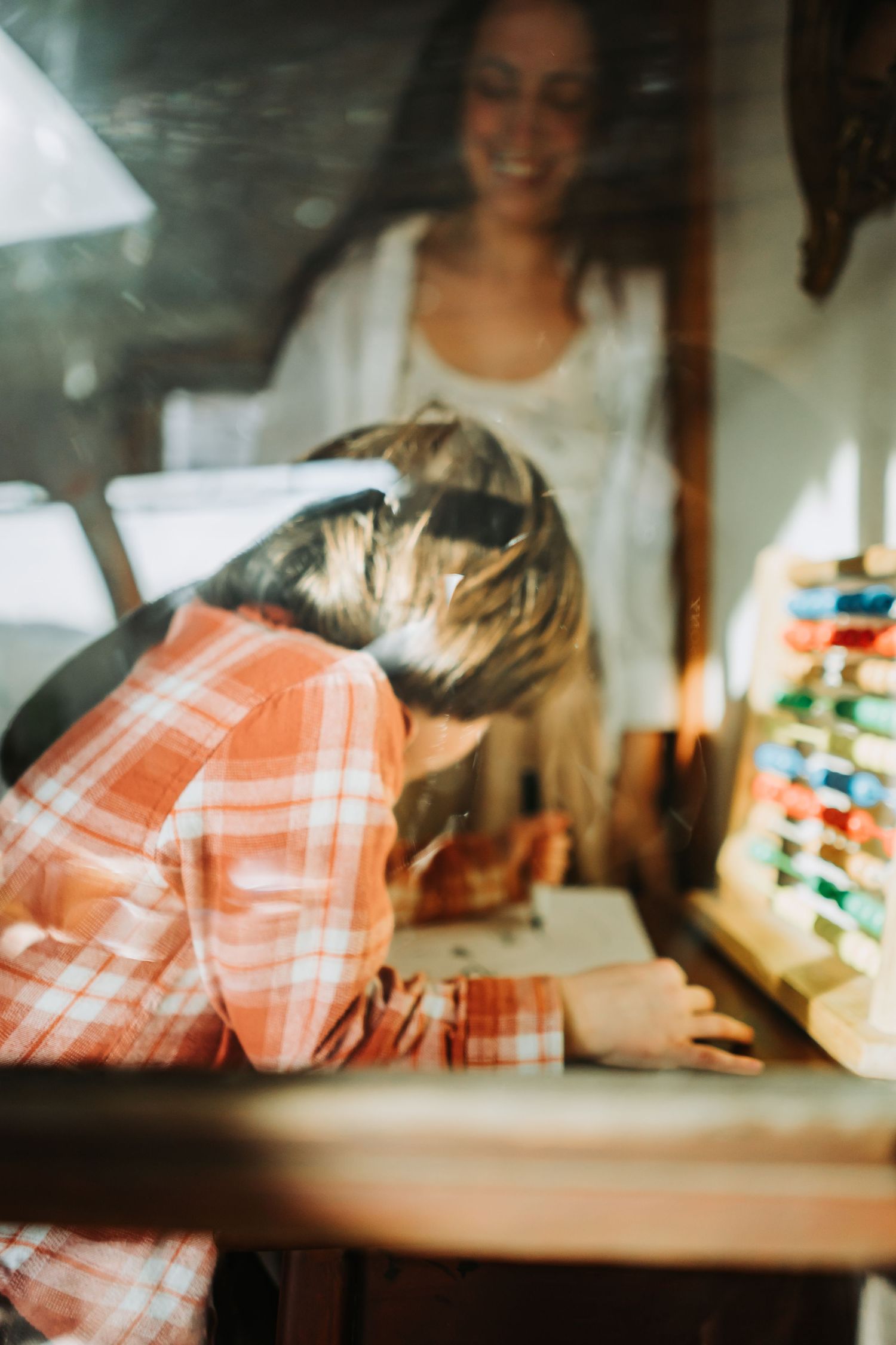 Person in plaid shirt engaging with an educational wooden toy or puzzle in a warm indoor setting.