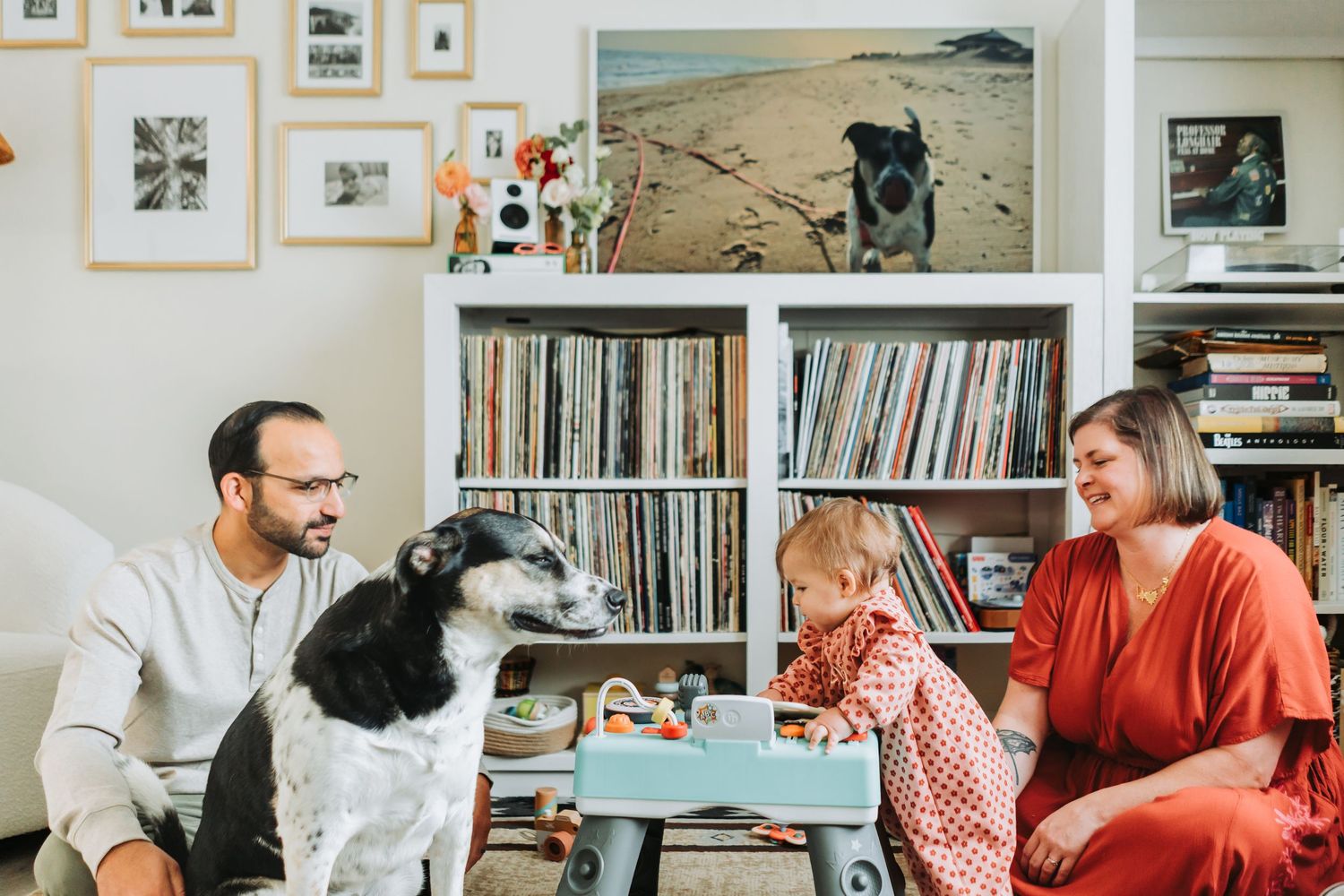 People gather in a cozy living room with bookshelves and artwork, engaged in animated conversation.