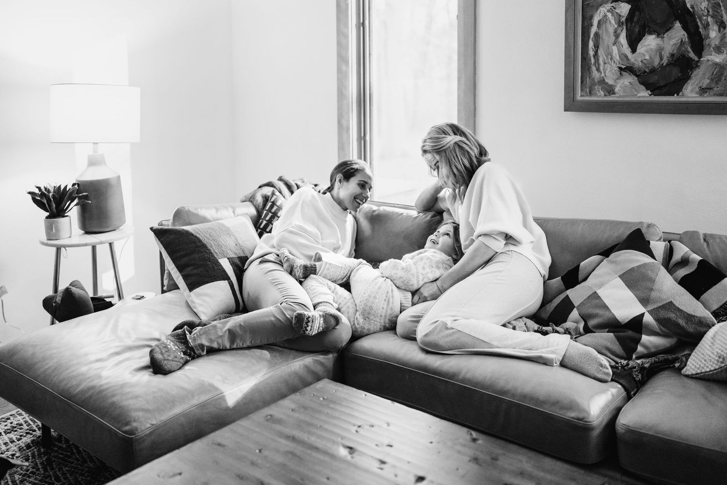 A candid black and white photograph of two people relaxing together on a comfortable sectional sofa in a living room.