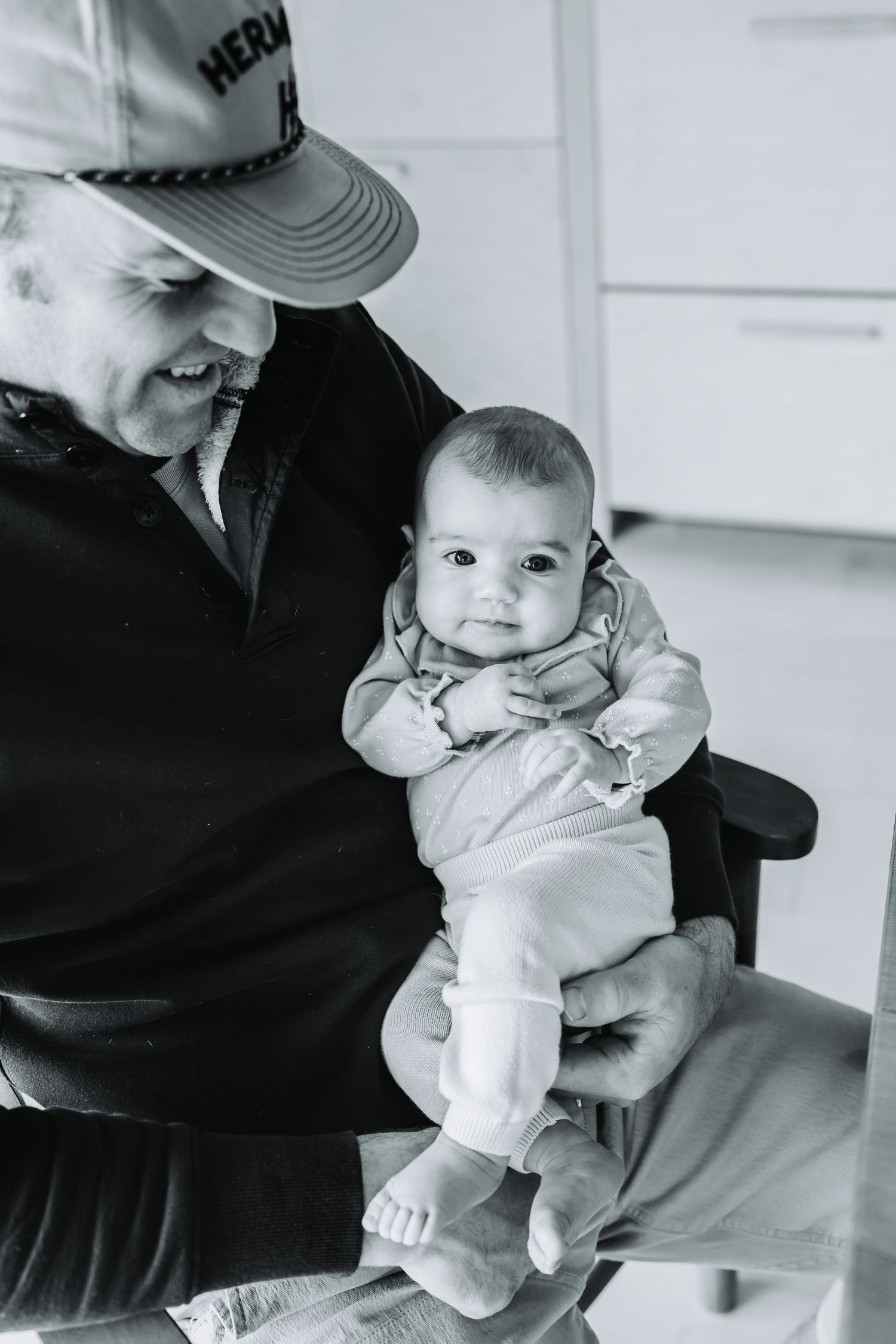 Black and white portrait of someone holding a small baby wearing light colored clothing.