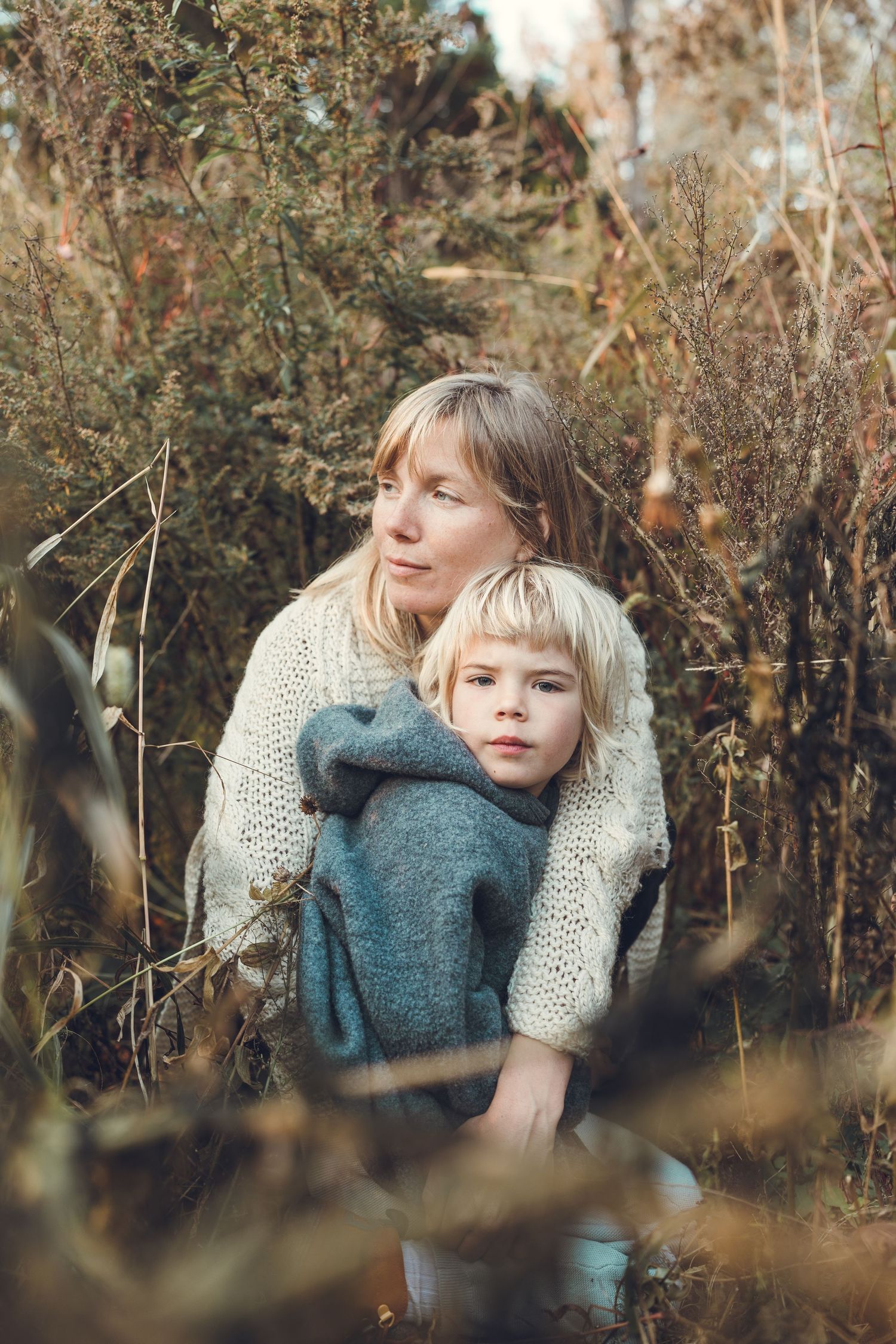 A loving embrace in an autumn forest setting showing a warm knit sweater and teal jacket.