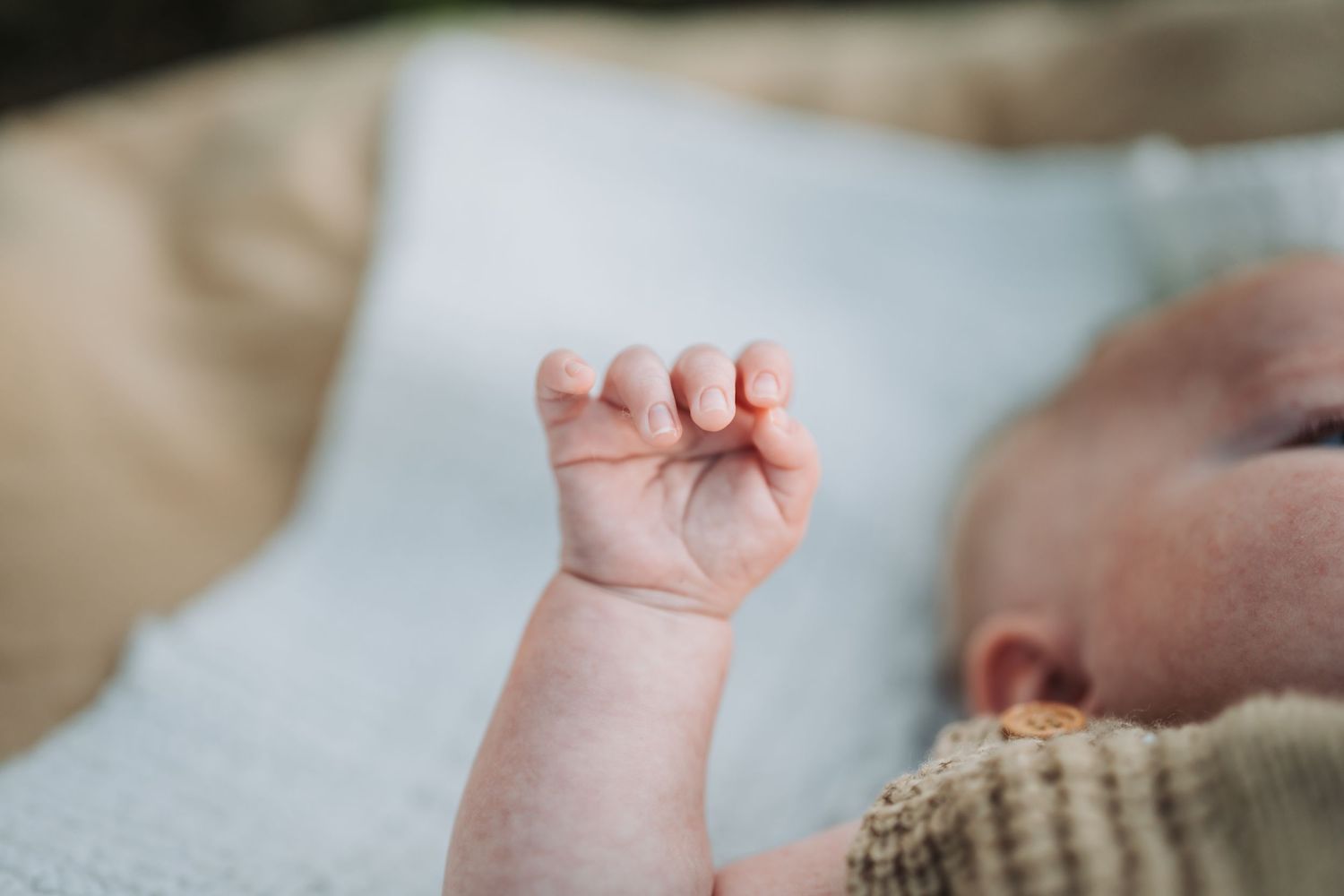 Sequence of close-up shots of a baby's small hand and arm reaching upward in a delicate manner.