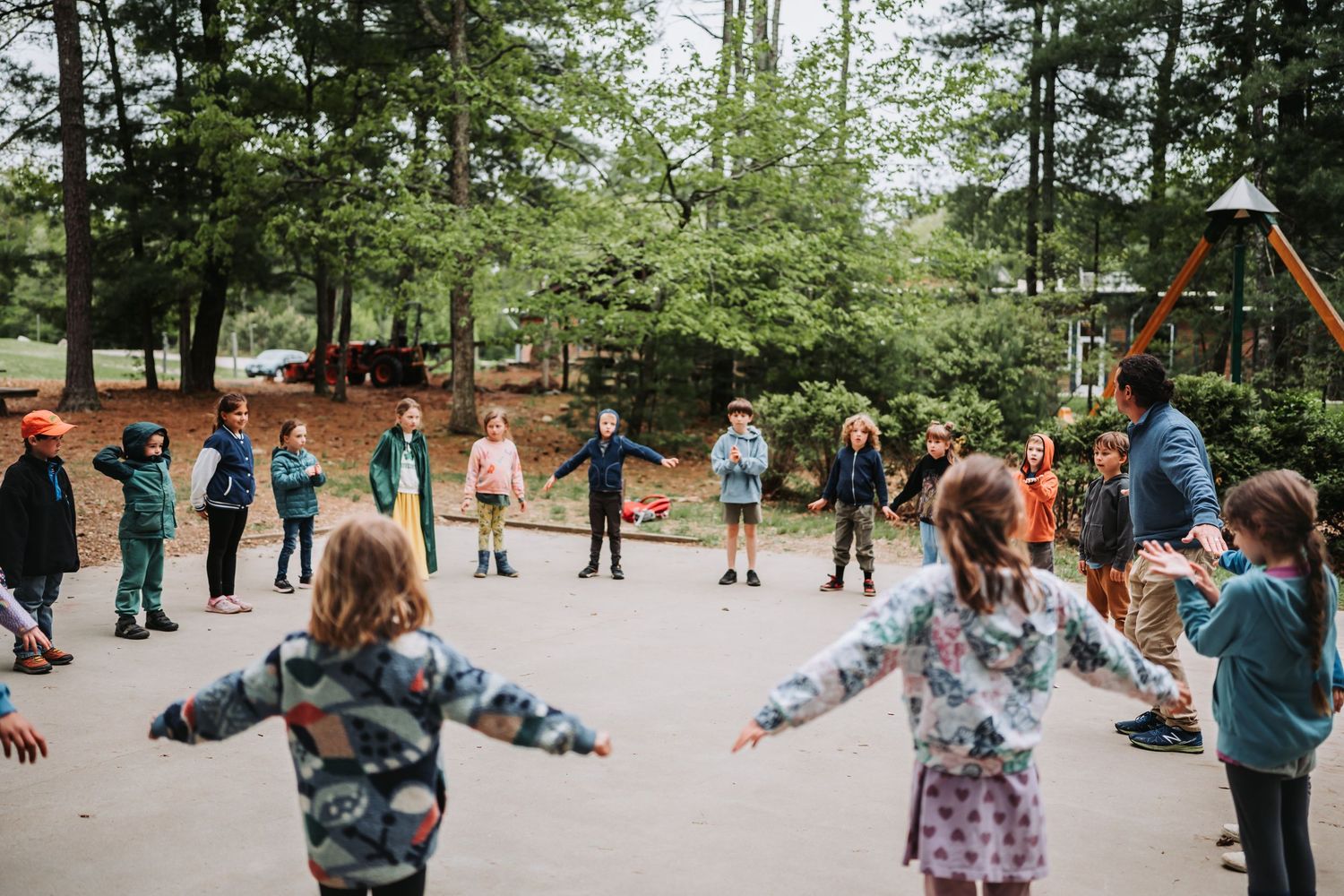 Students participate in an outdoor group activity on a sunny day in a wooded area.